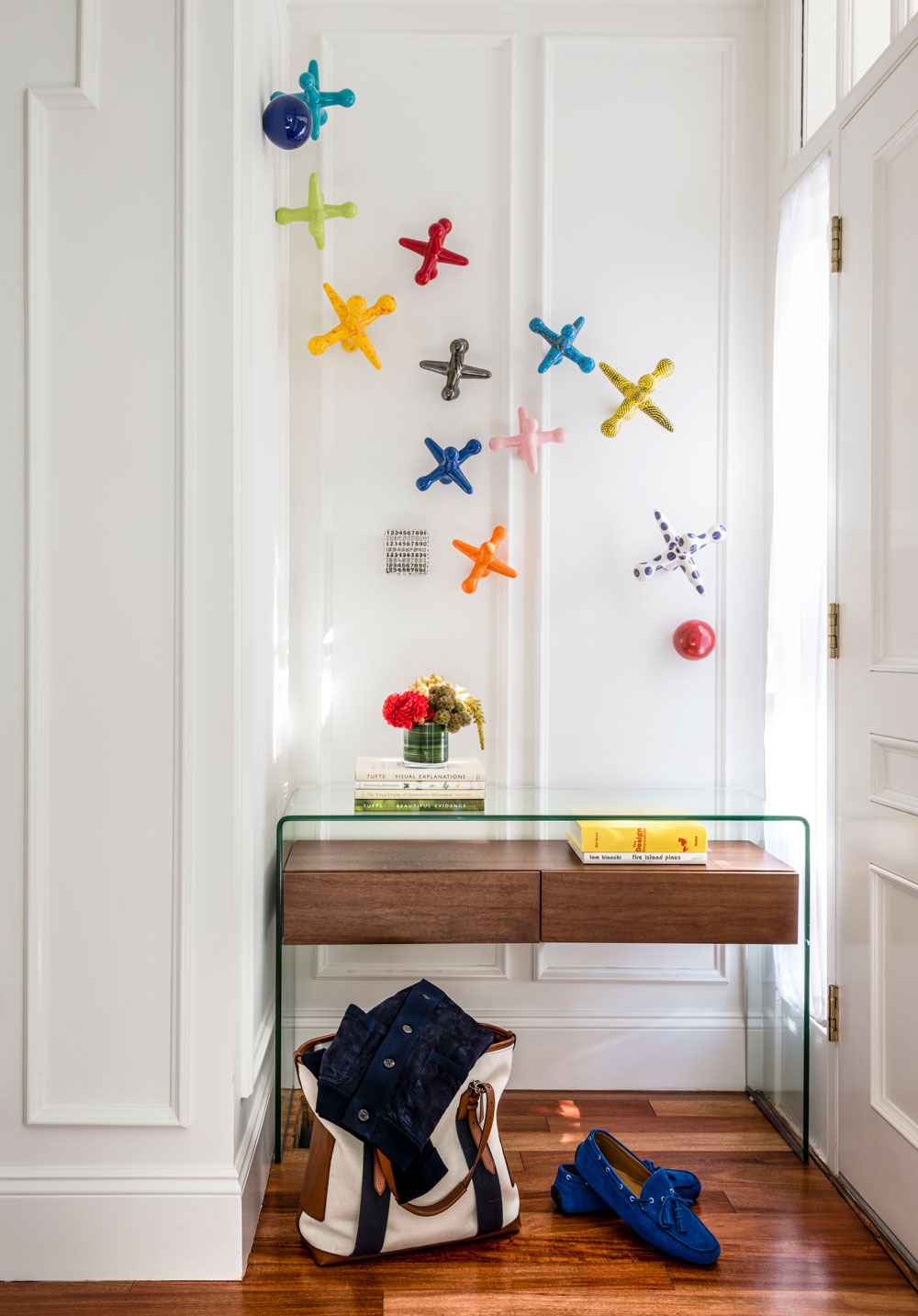 Beneath the ceramic jacks in the entry, a glass waterfall console with a wood inset lends the appearance of a floating shelf.