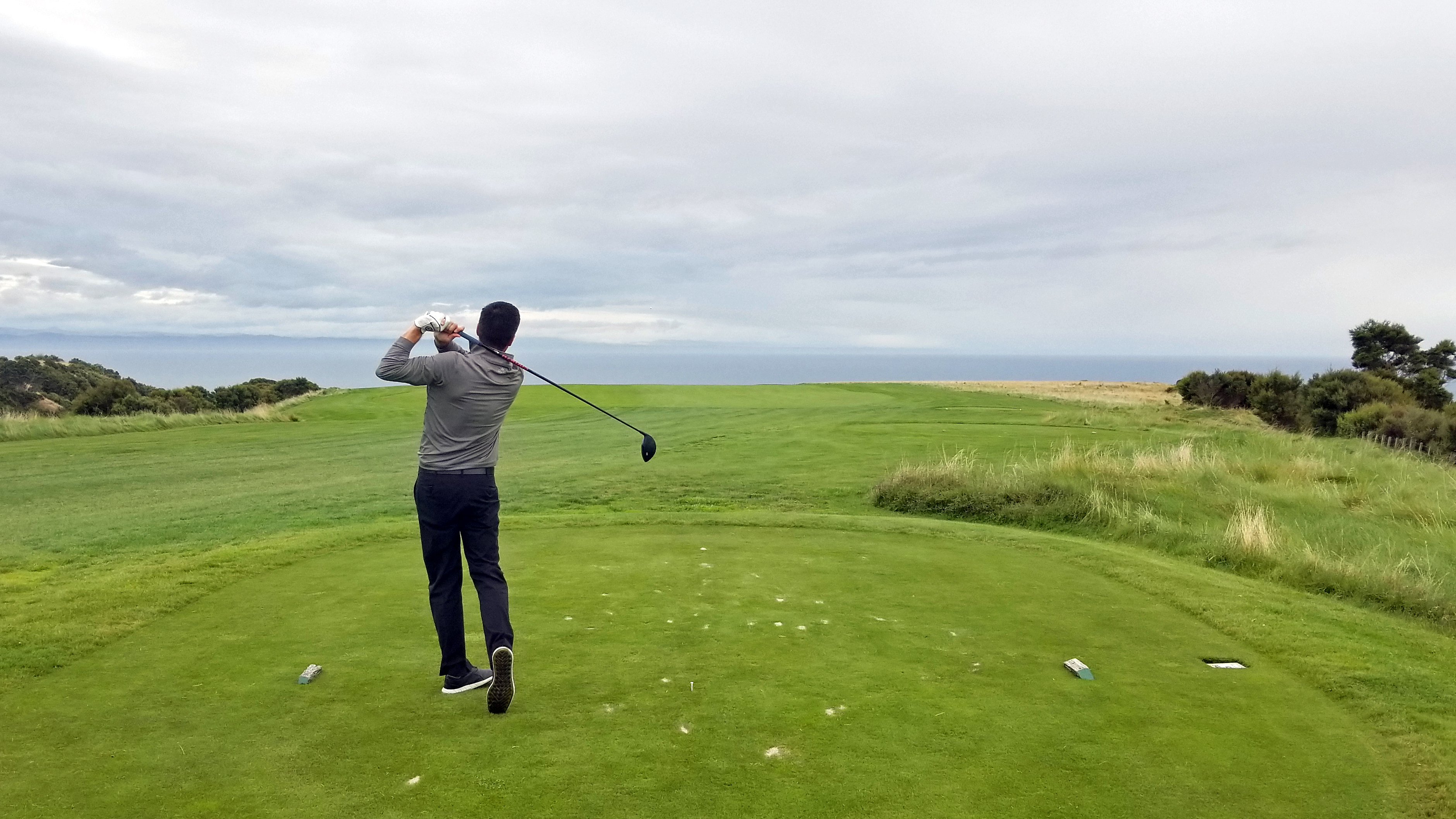 With the Pacific Ocean as a backdrop, Ryan Brandeburg of Golf Tourism New Zealand hits a tee shot on the spectacular Cape Kidnappers golf course.