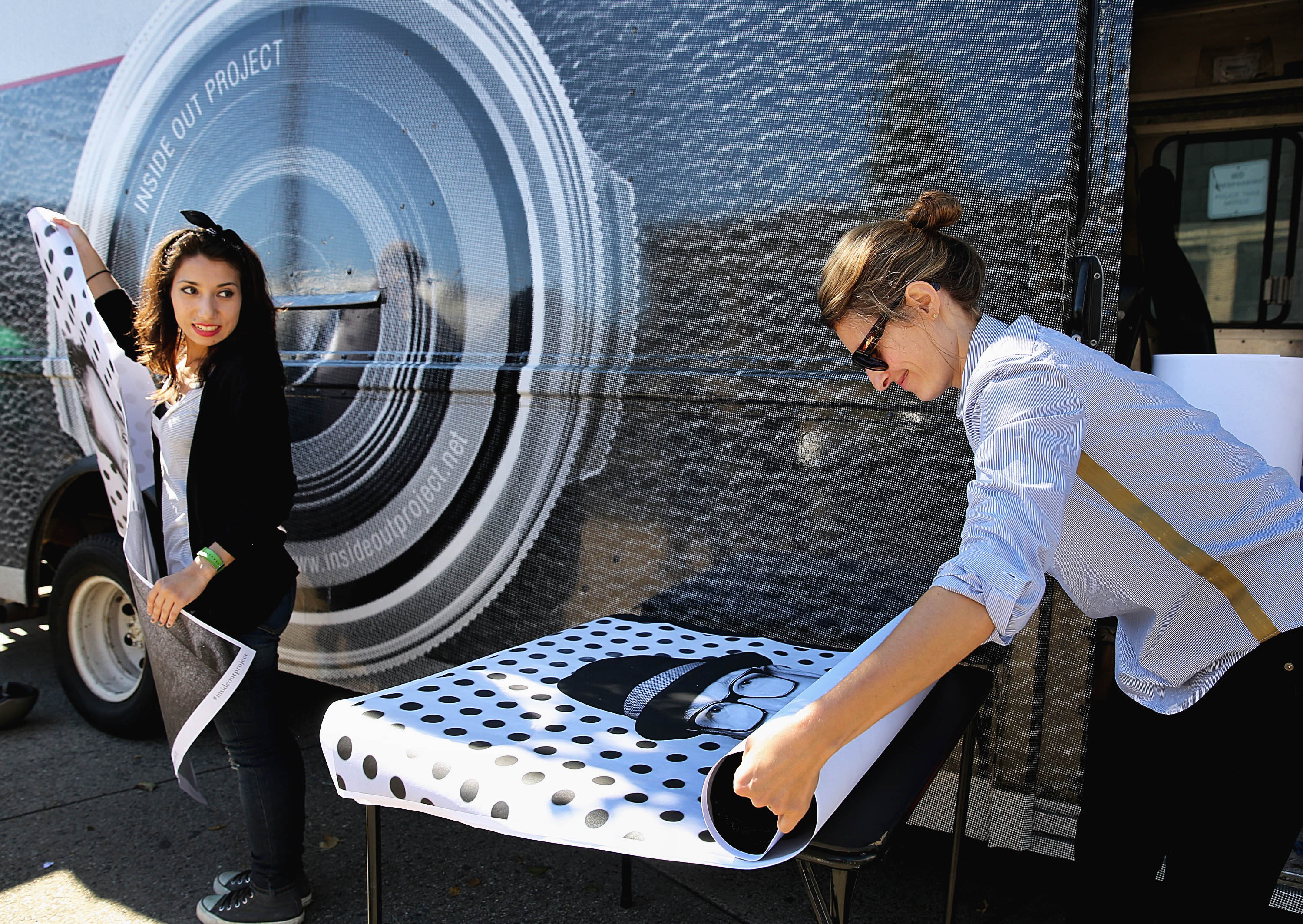 Volunteers Jennifer Guarracino, left, and Martina Tanga gathered giant xerox prints of residents whose photos were taken as part of the Inside Out Project outside the Dudley Branch, Boston Public Library in Roxbury.