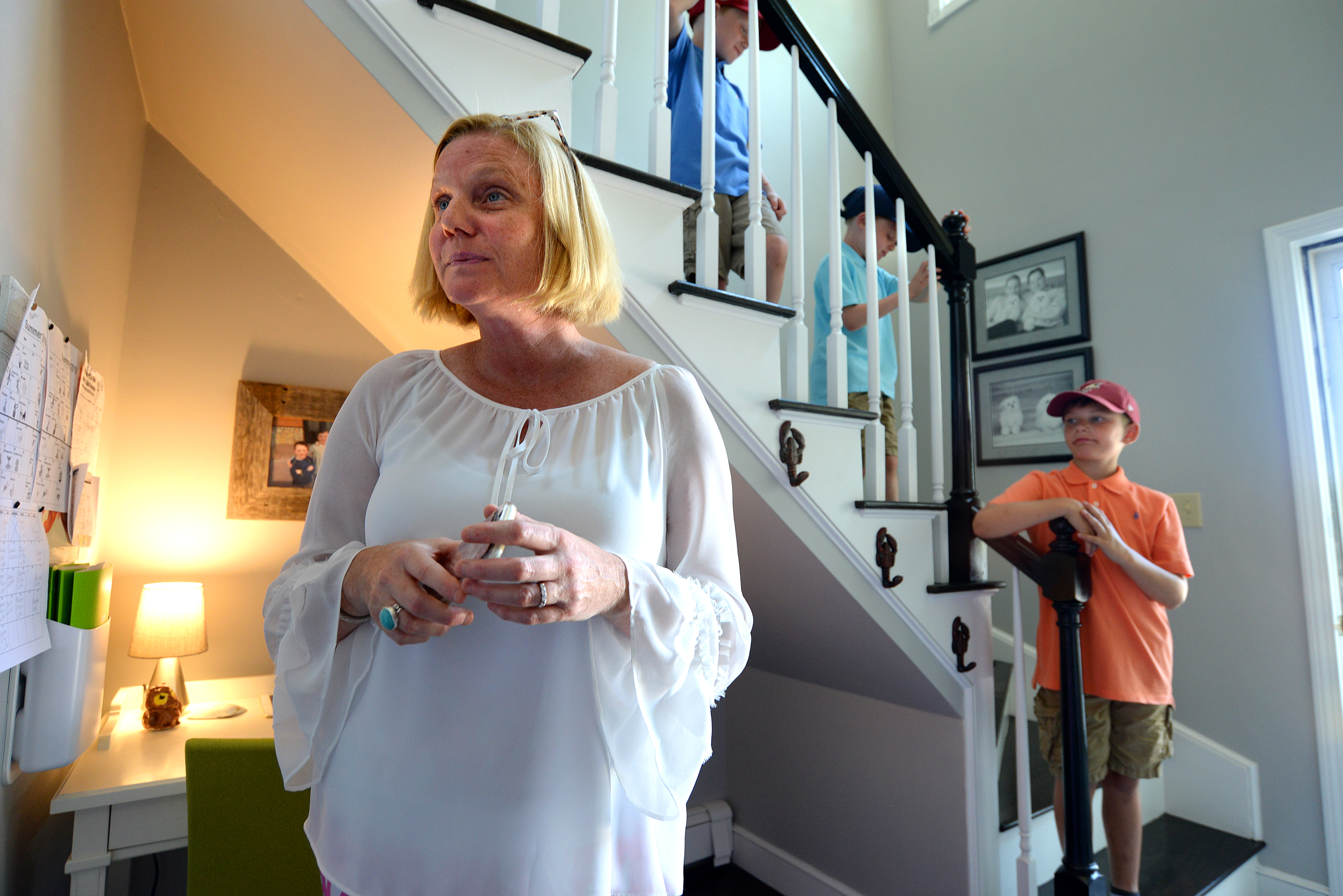 Lisa Blake, a professional organizer, stands next to her Command Central space in the corner of the staircase of her Scituate home. Her sons on the stairs (from left): Wyatt Maldonis, his twin Hunter, 8, Mason, 9.