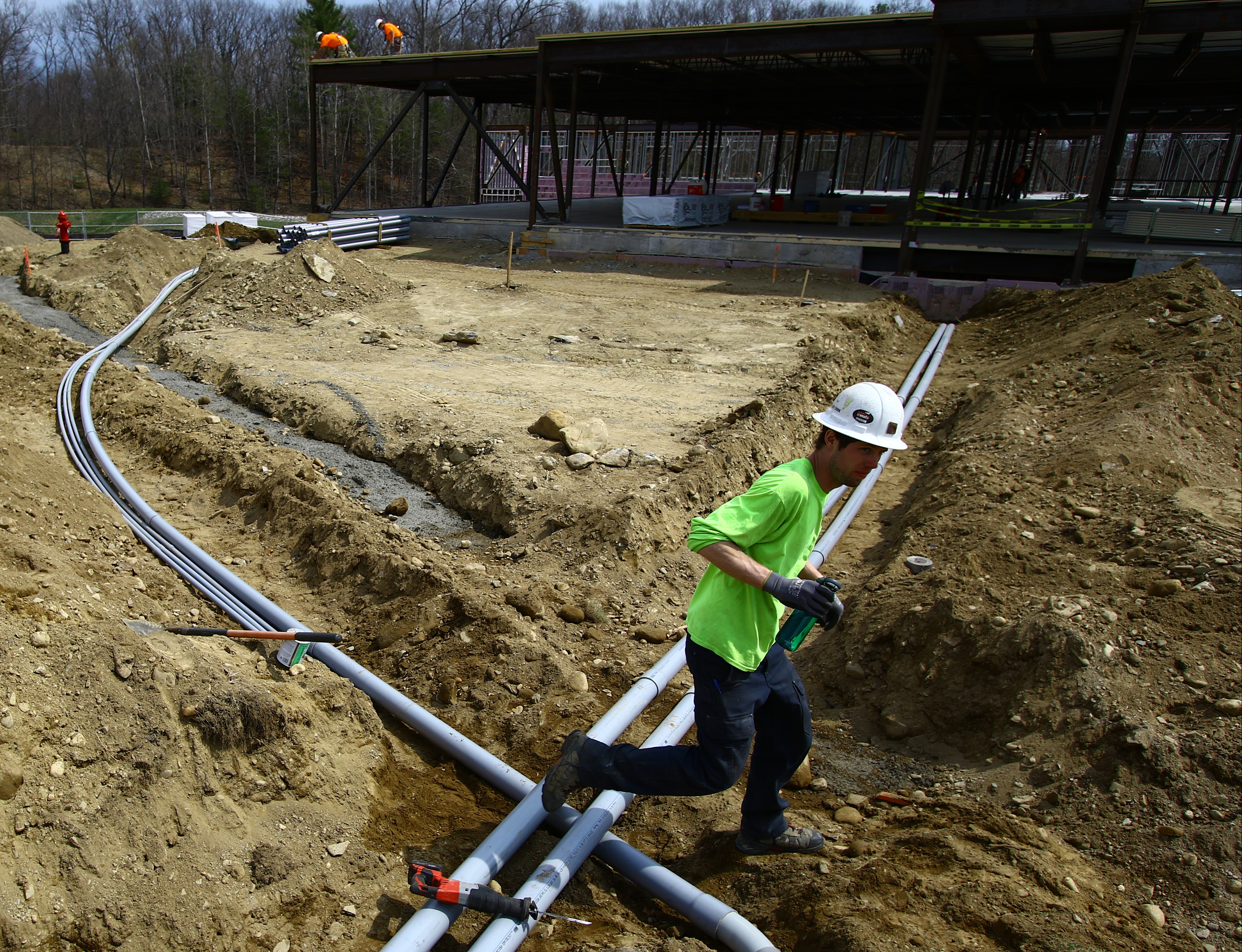 An electrical worker crossed a ditch with tubing at the Devens construction site.