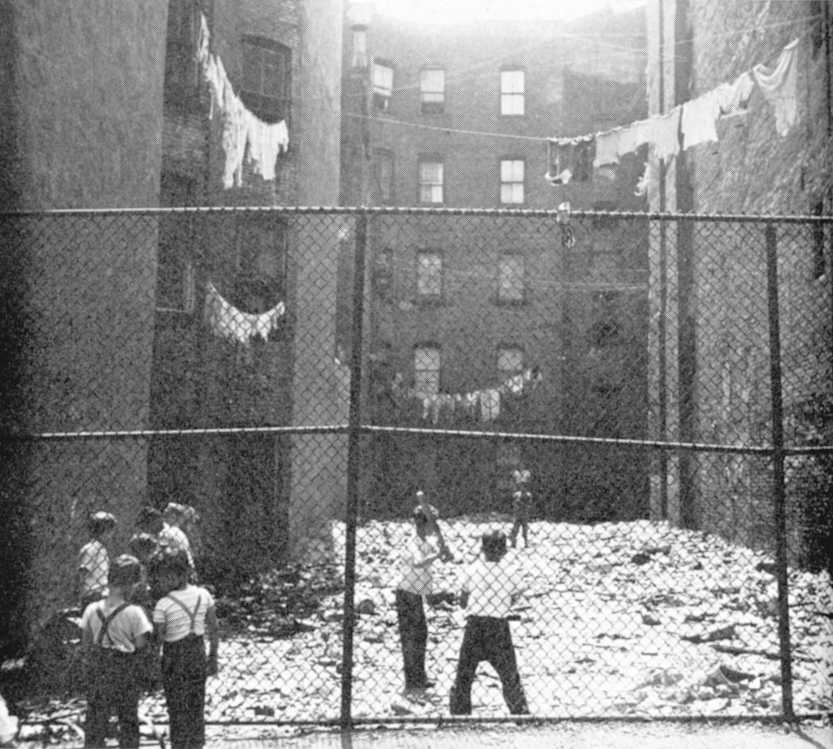 New York City children play stickball in a fenced-in back lot on the Lower East Side in 1951.