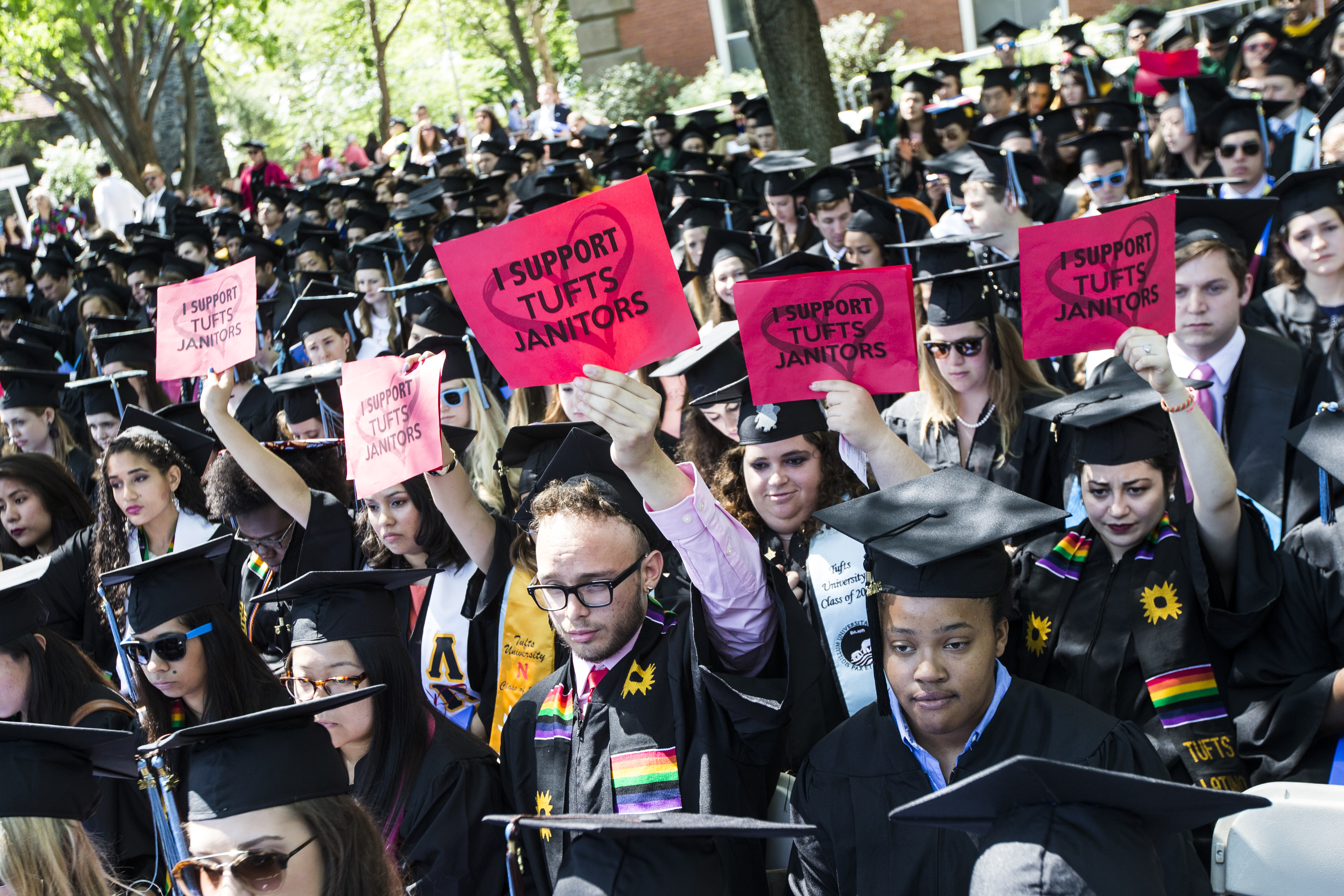 Dozens of graduates held red signs during the commencement ceremony, with the words “I support Tufts janitors” on a heart shape.