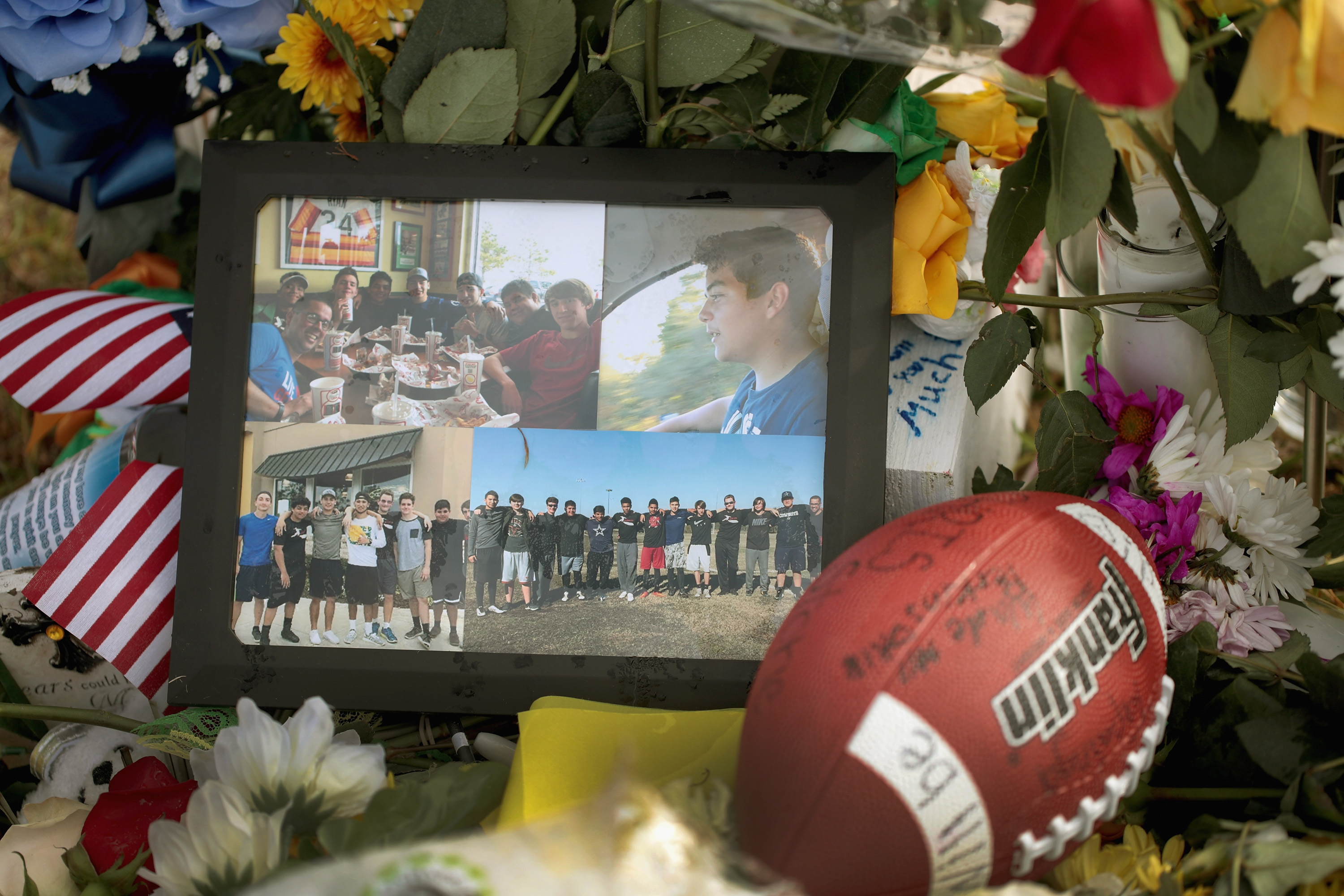 Photos, a football and flowers sit in front of a cross bearing the name of Chris Stone.