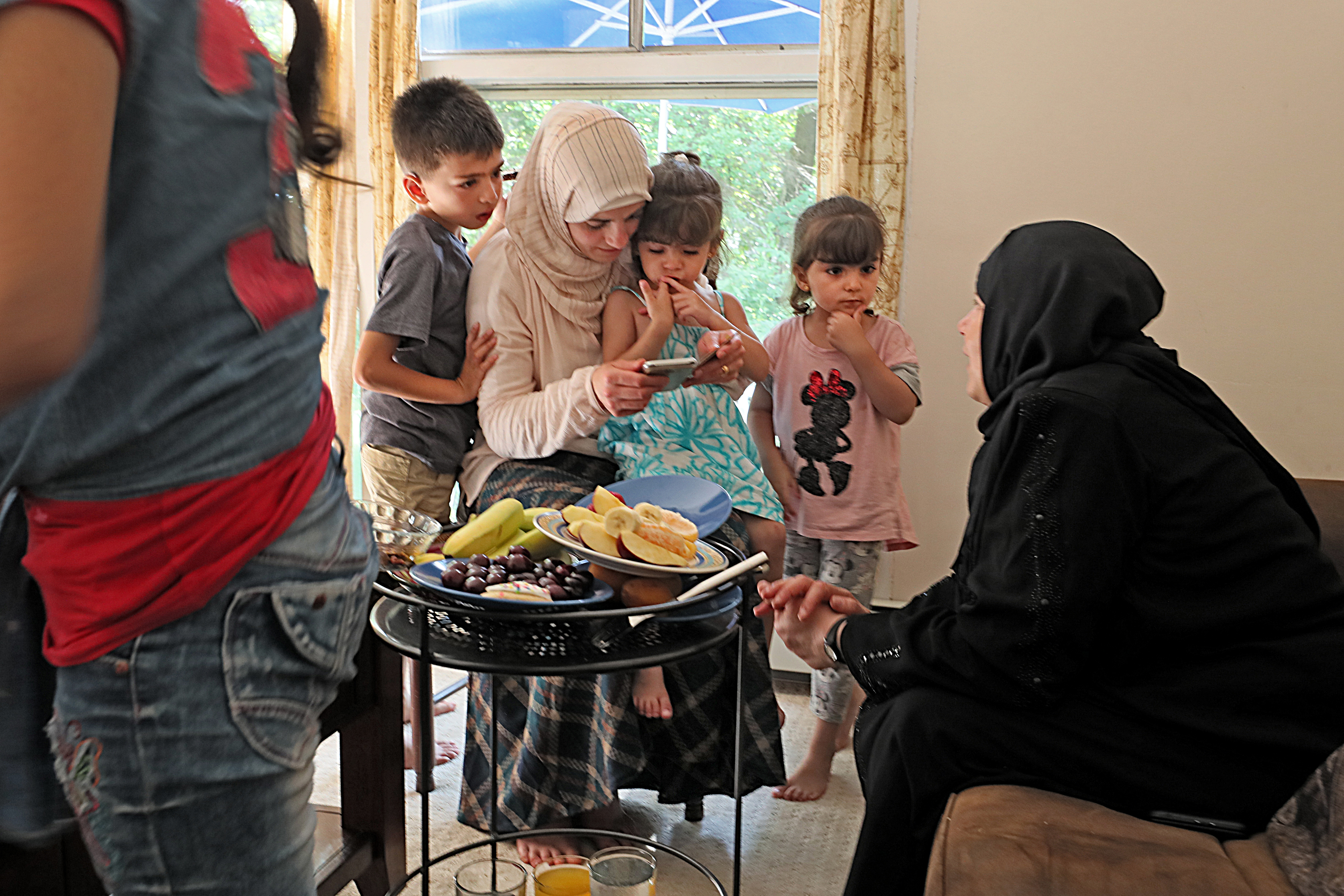 After her successful day at Walden Pond, Asmaa and Abdulkader hosted another newly arrived Syrian family for dinner at their home, Asmaa offering knowing advice and comfort. Ali, Ameeneh, Fatimah, and their mother, Asmaa, looked at photos of the new Syrian mother’s older children who could not get visas to America.