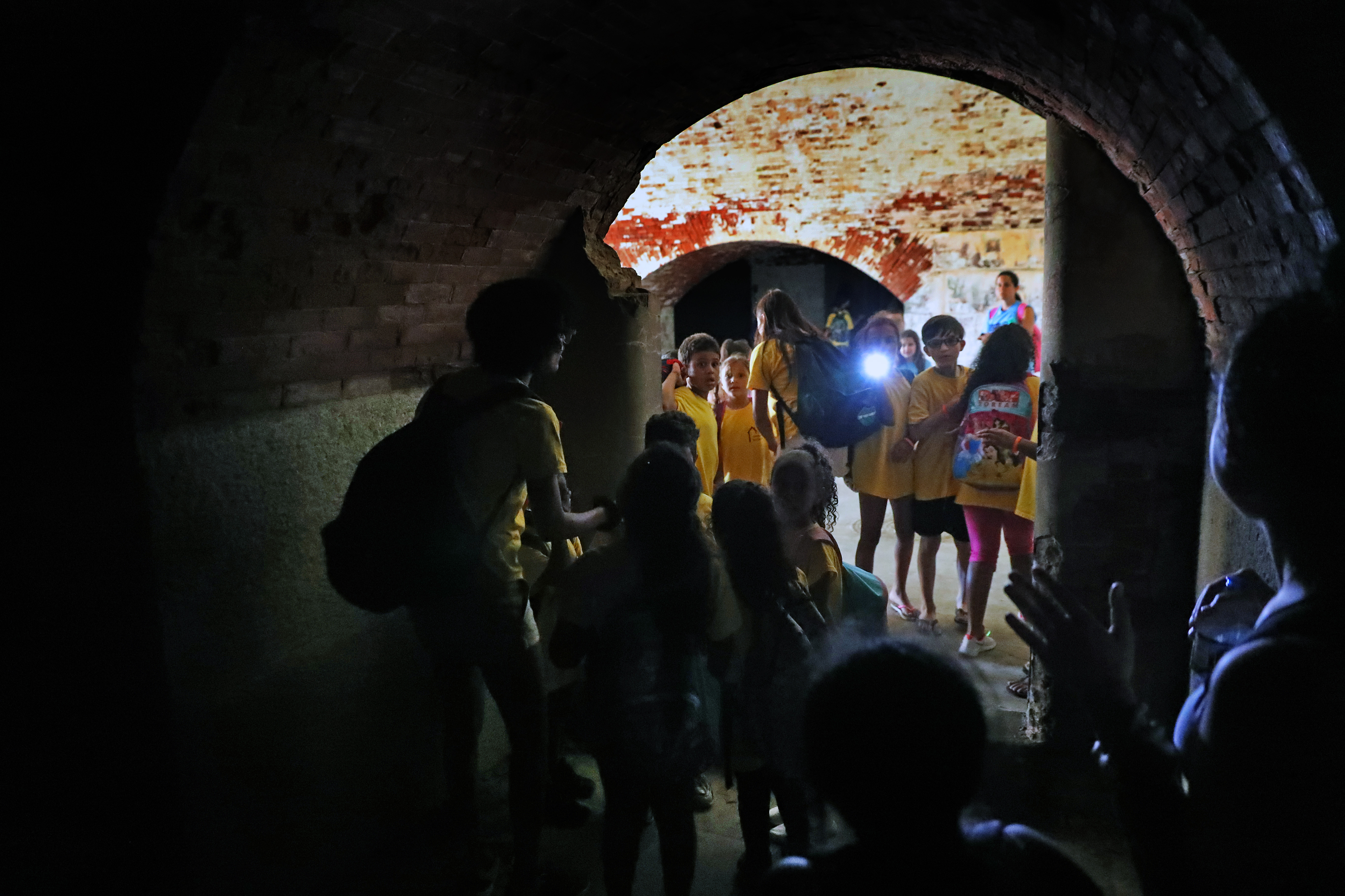 Visitors explored the caverns of Fort Warren, which can be dark enough to require a flashlight for safe passage.