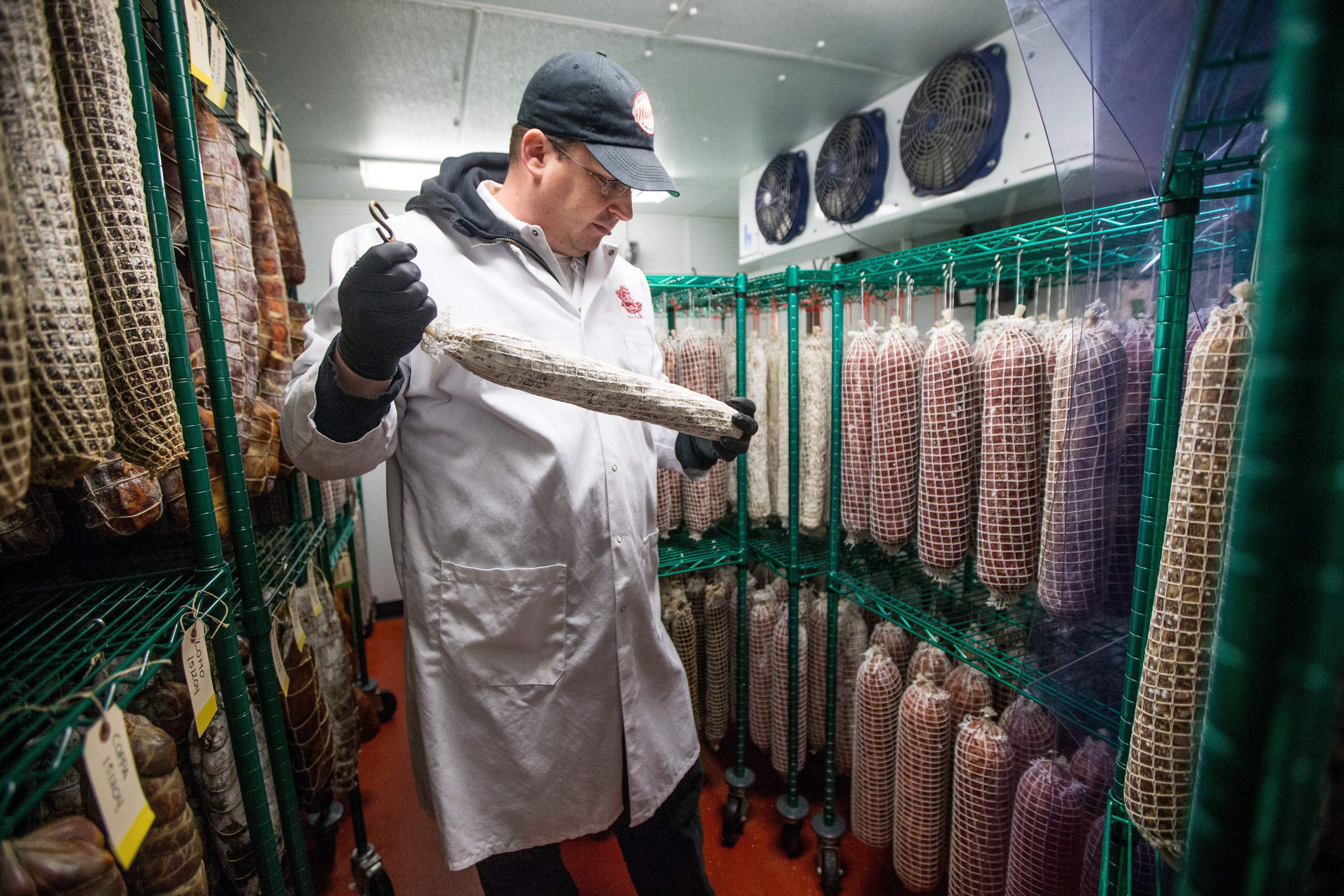 Joshua Smith hanging cured meats at his Waltham shop.