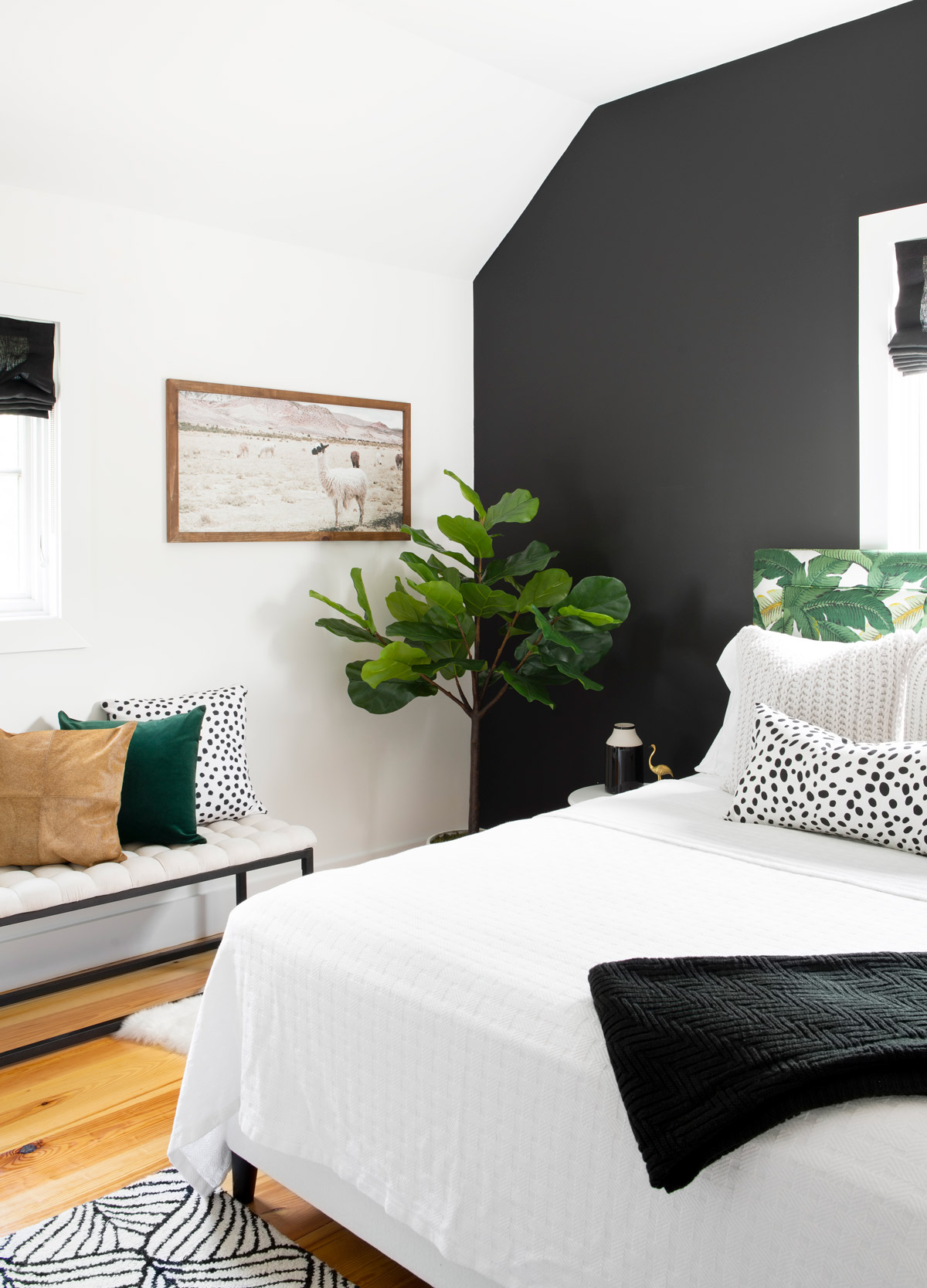 The headboard, upholstered in a tropical leaf print, pops against the black accent wall in one of the home’s two guest bedrooms. The llama print is from World Market.