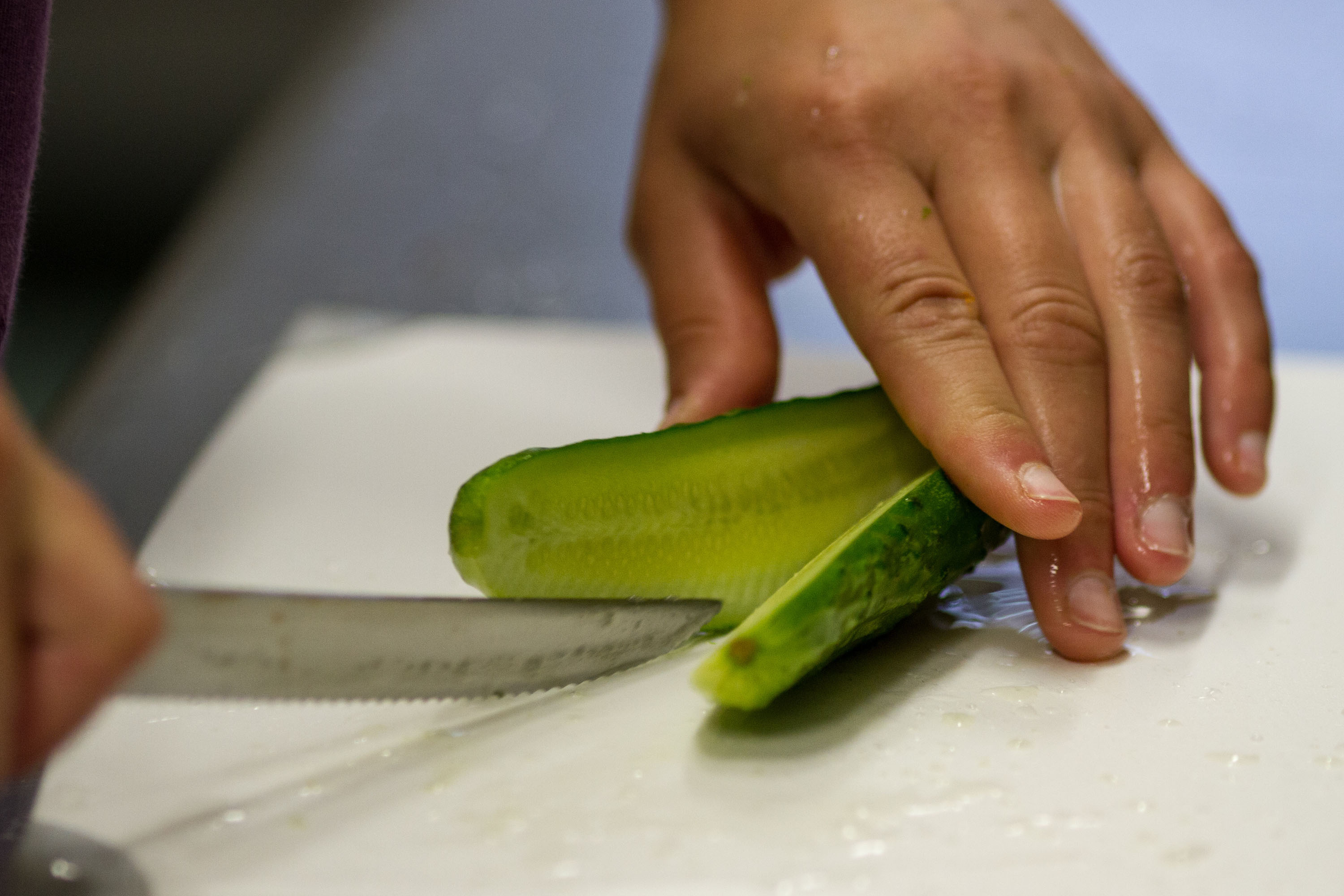 A pickle maker cuts an organic cucumber.