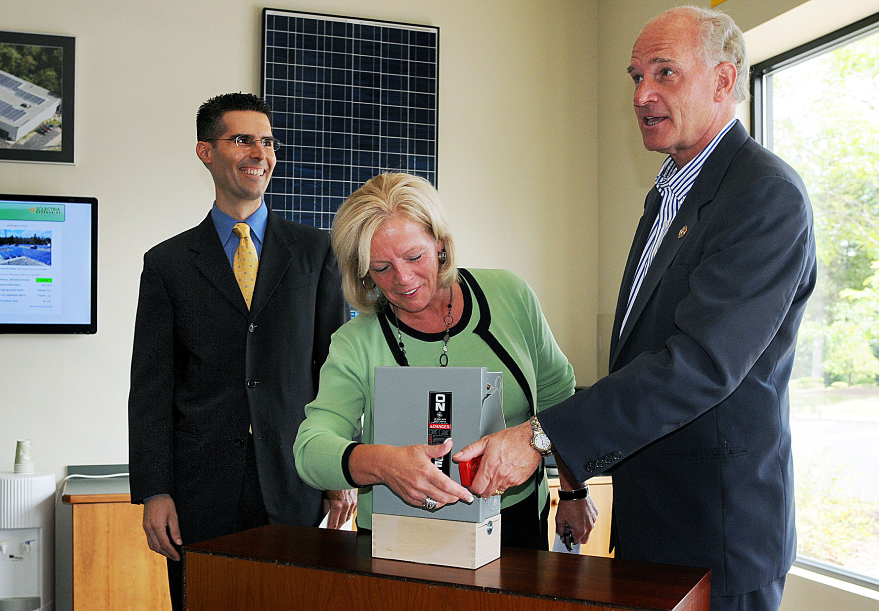Jeff Morrill (left) watches as state Representative Rhonda Nyman and US Representative Bill Keating flip the switch.
