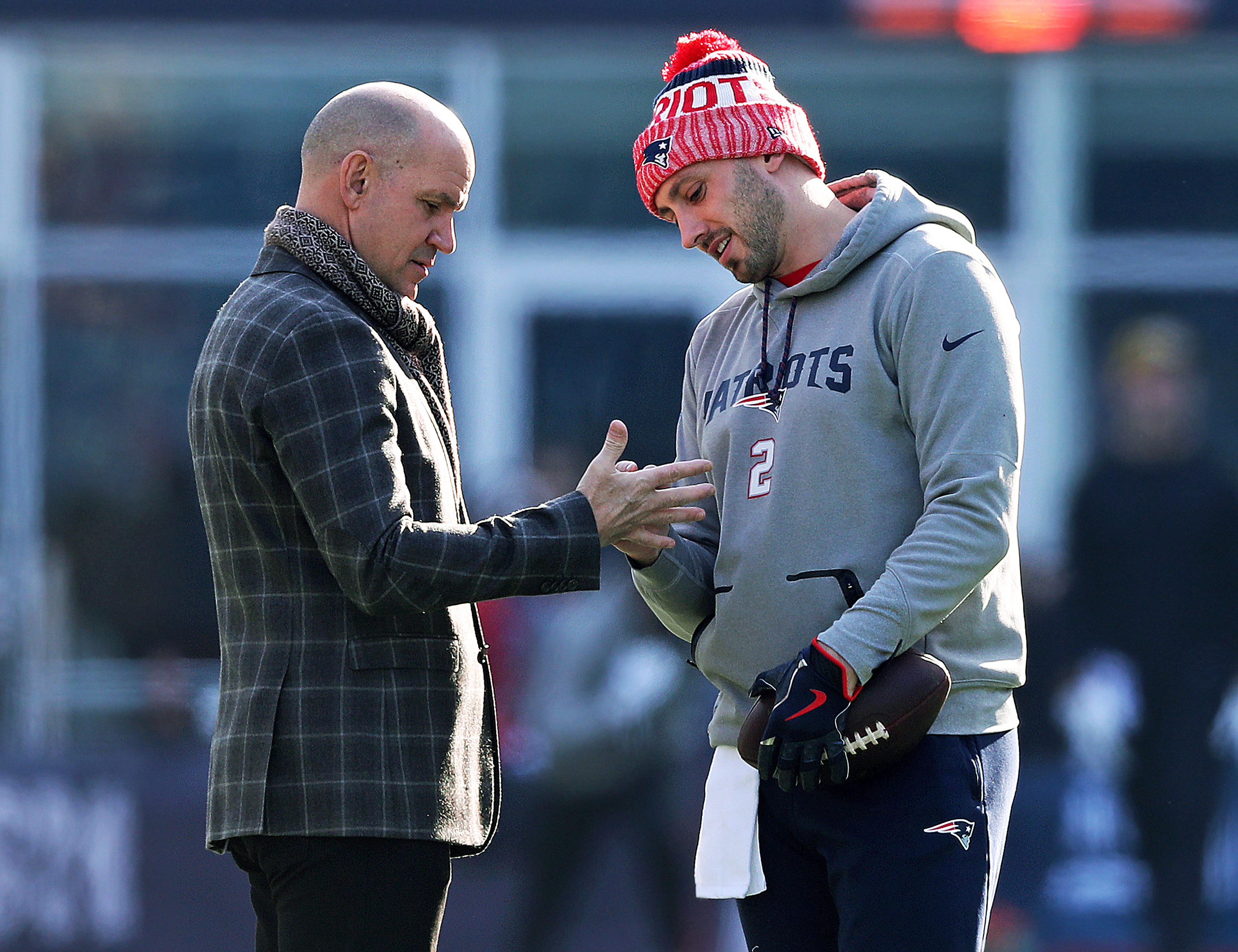 About two hours before kickoff, Patriots backup quarterback Brian Hoyer (right) was out throwing some passes, when he stopped and was pointing out a spot on an unidentified man's right hand.