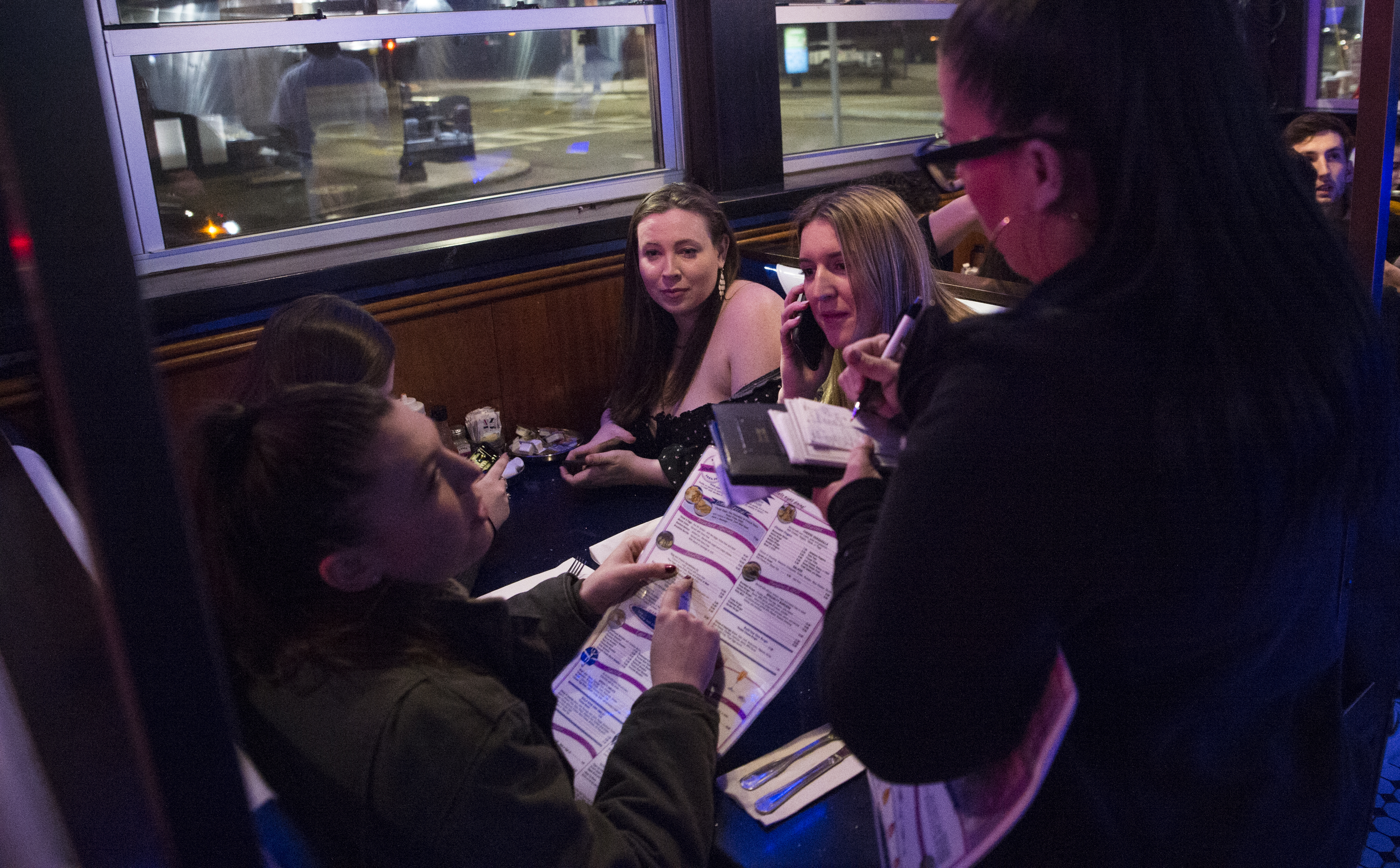 Kelly Bakker spoke on her phone next to Caitlin Reid with their friends Maeve Parahua and Casey Osborne while getting their order taken at South Street.