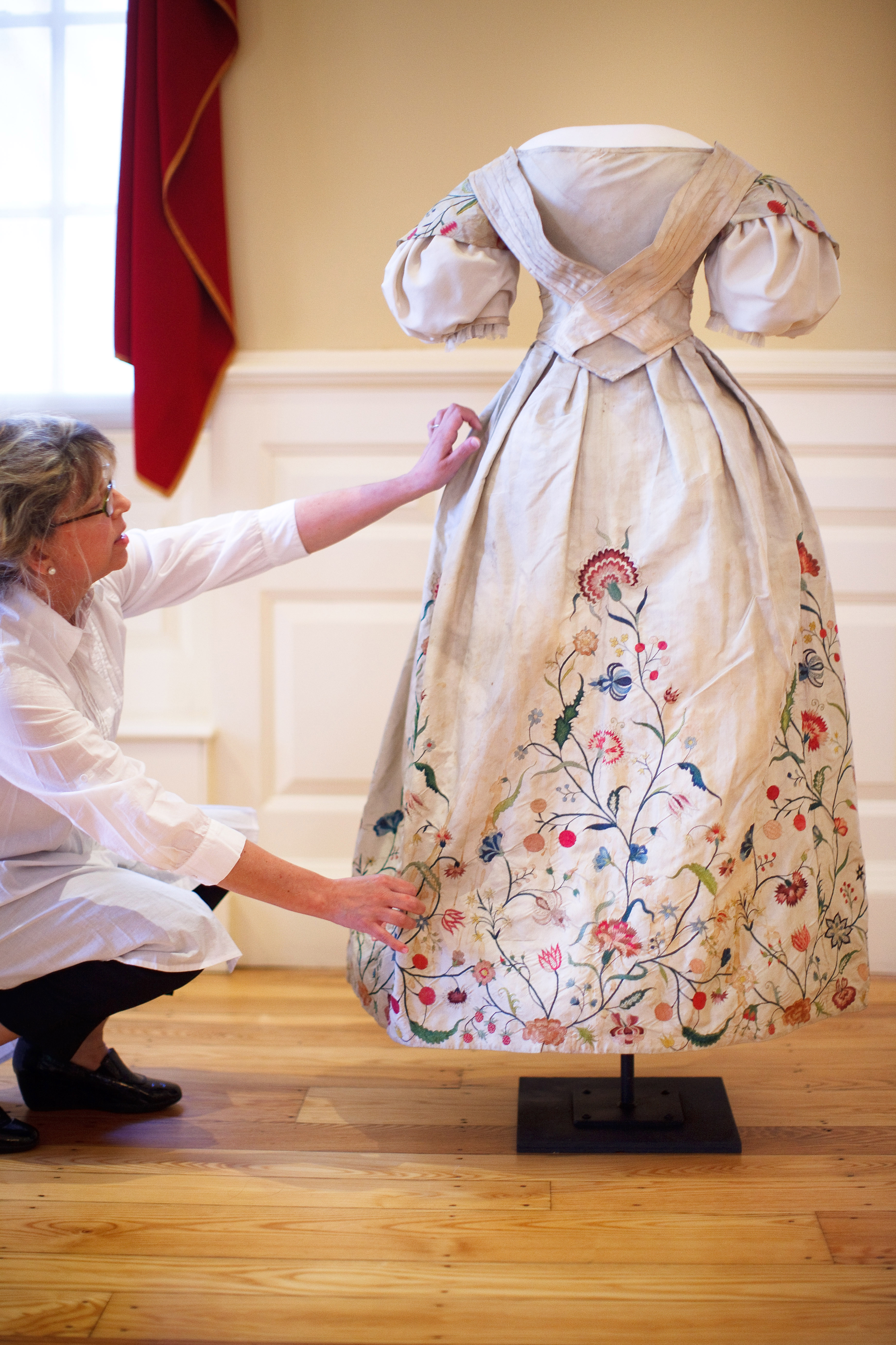 Fashion historian Kimberly Alexander arranges the Elizabeth Bull Colonial wedding dress, which dates back to 1730, for viewing.