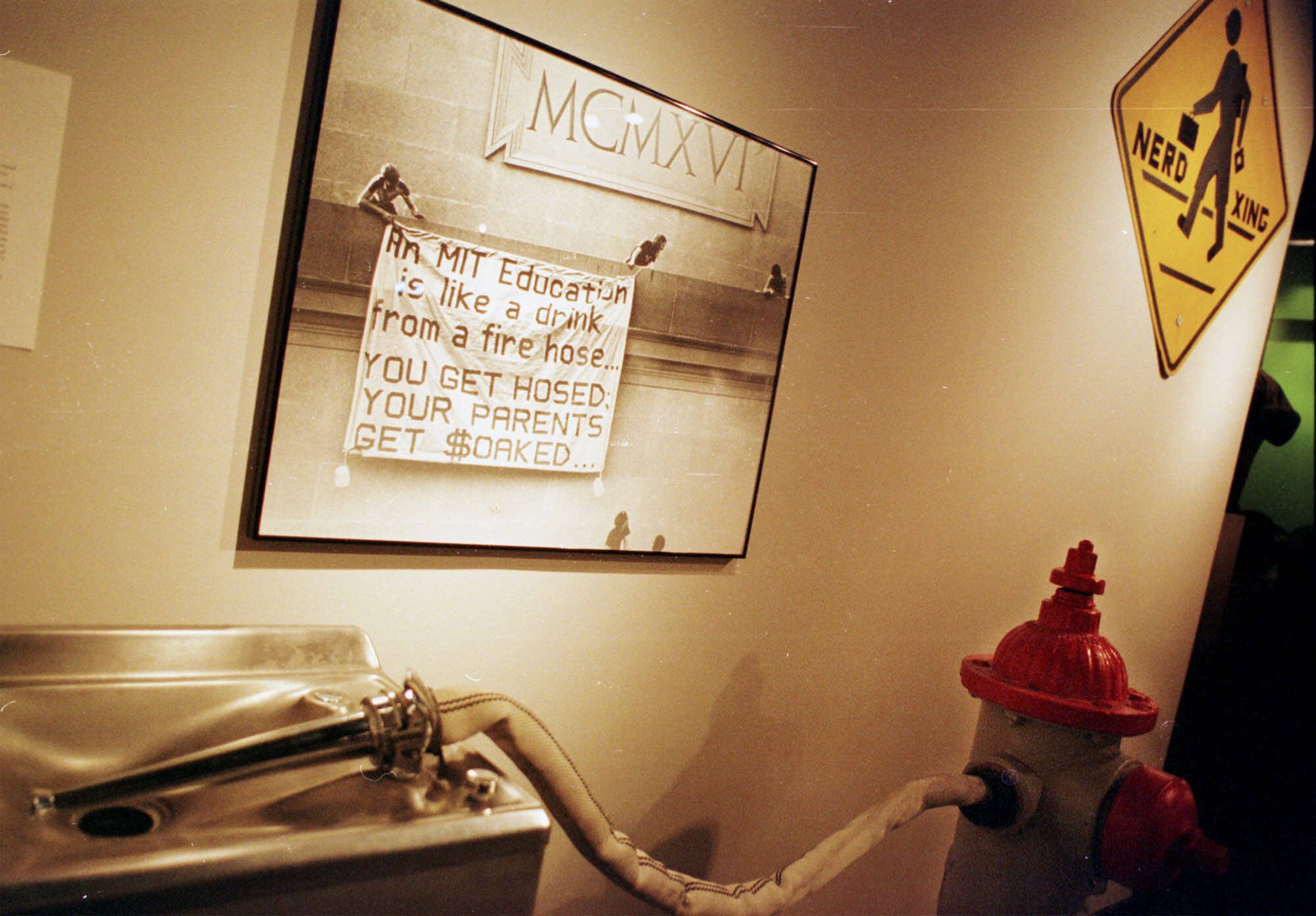 Inside the Hall of Hacks exhibit is a display honoring one of MIT’s favorite expressions. Above is a photo of an old banner hack, while below it is the water fountain fire hydrant hack.