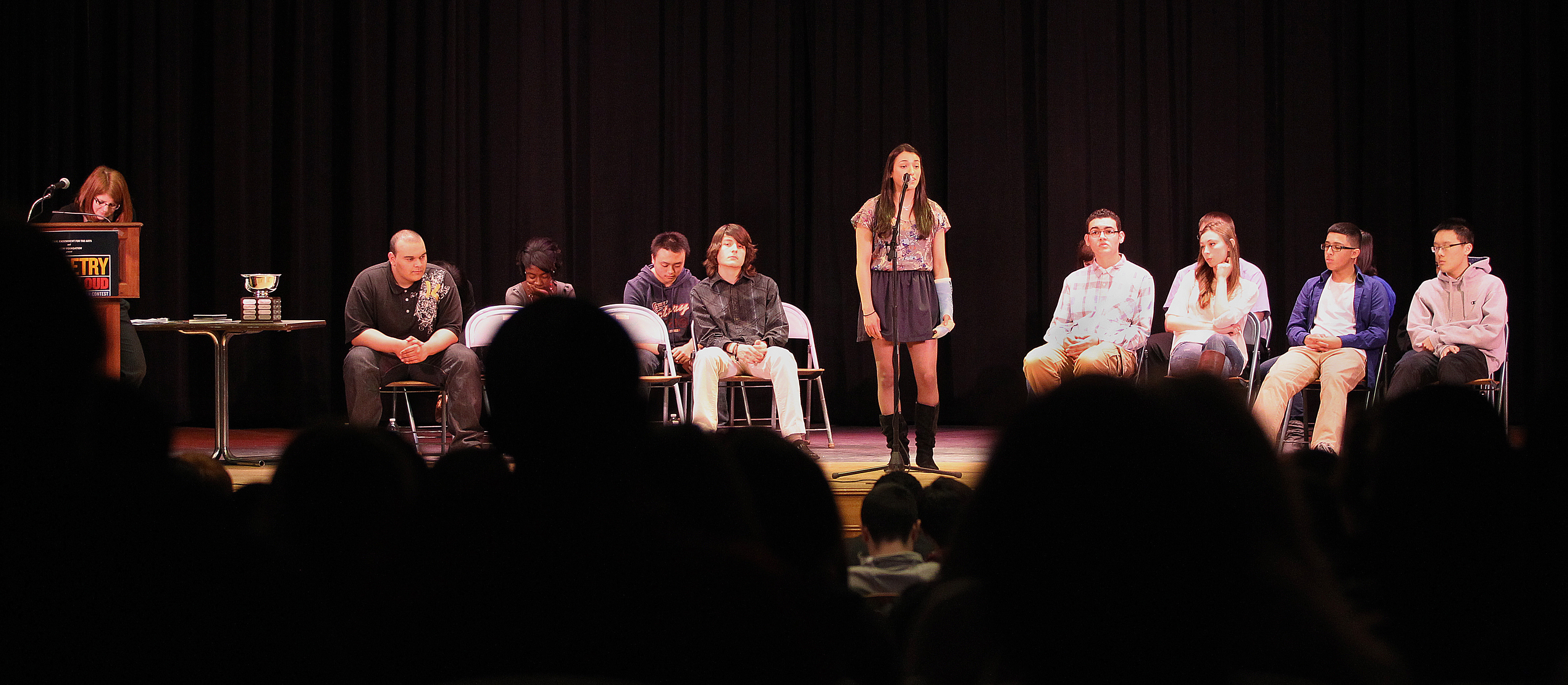 At the schoolwide finals at Malden High in January, senior Alana Casey recites a poem while her fellow competitors wait their turn.
