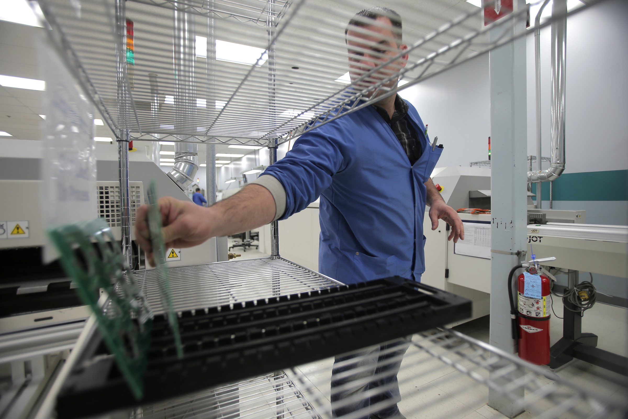 George Haynes placed circuit boards on a rack after pulling them from a reflow oven.
