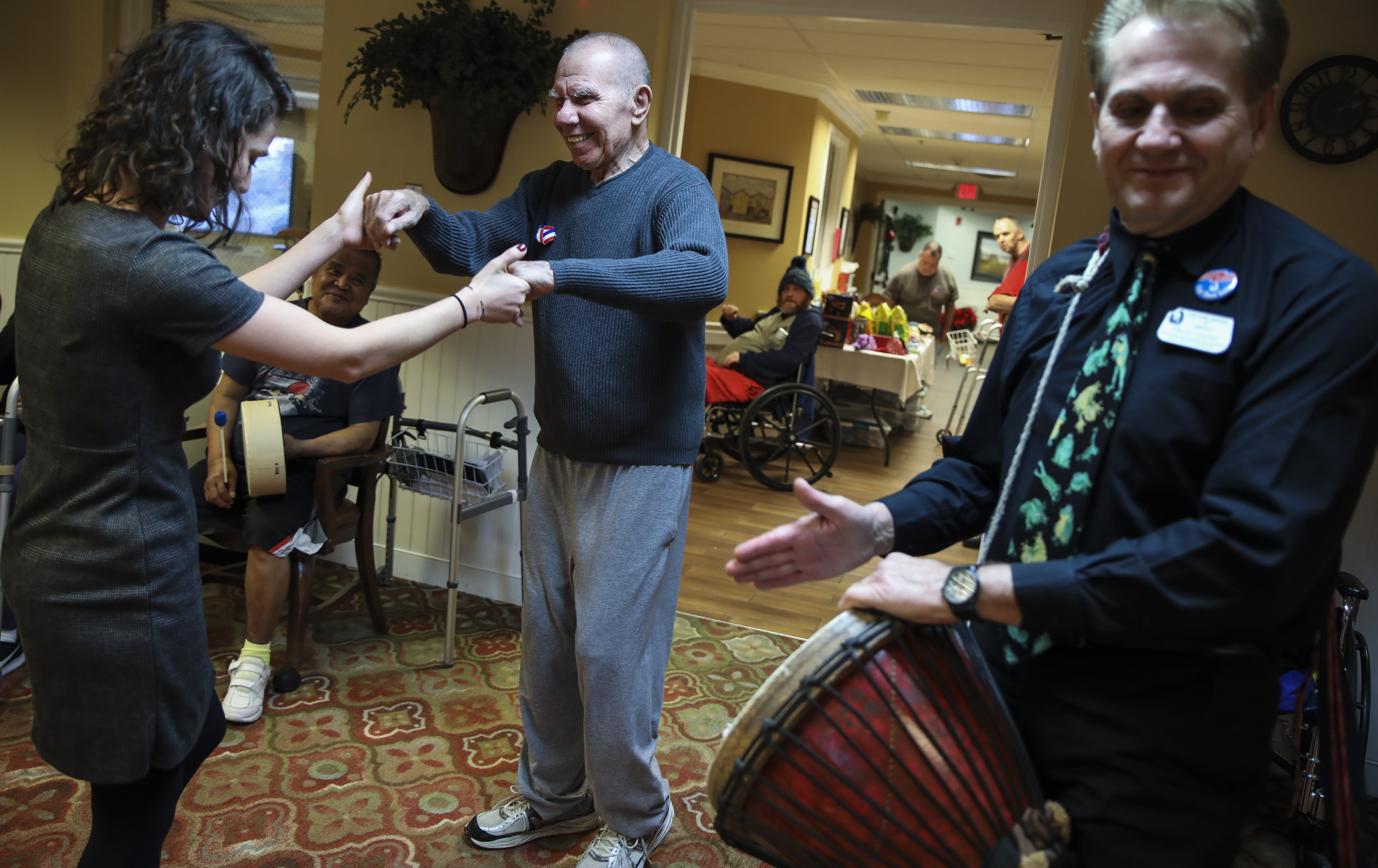 Carla Ciaramella (left), executive director of Life Care Center of the North Shore, danced with a patient while David Currier drummed Christmas carols.