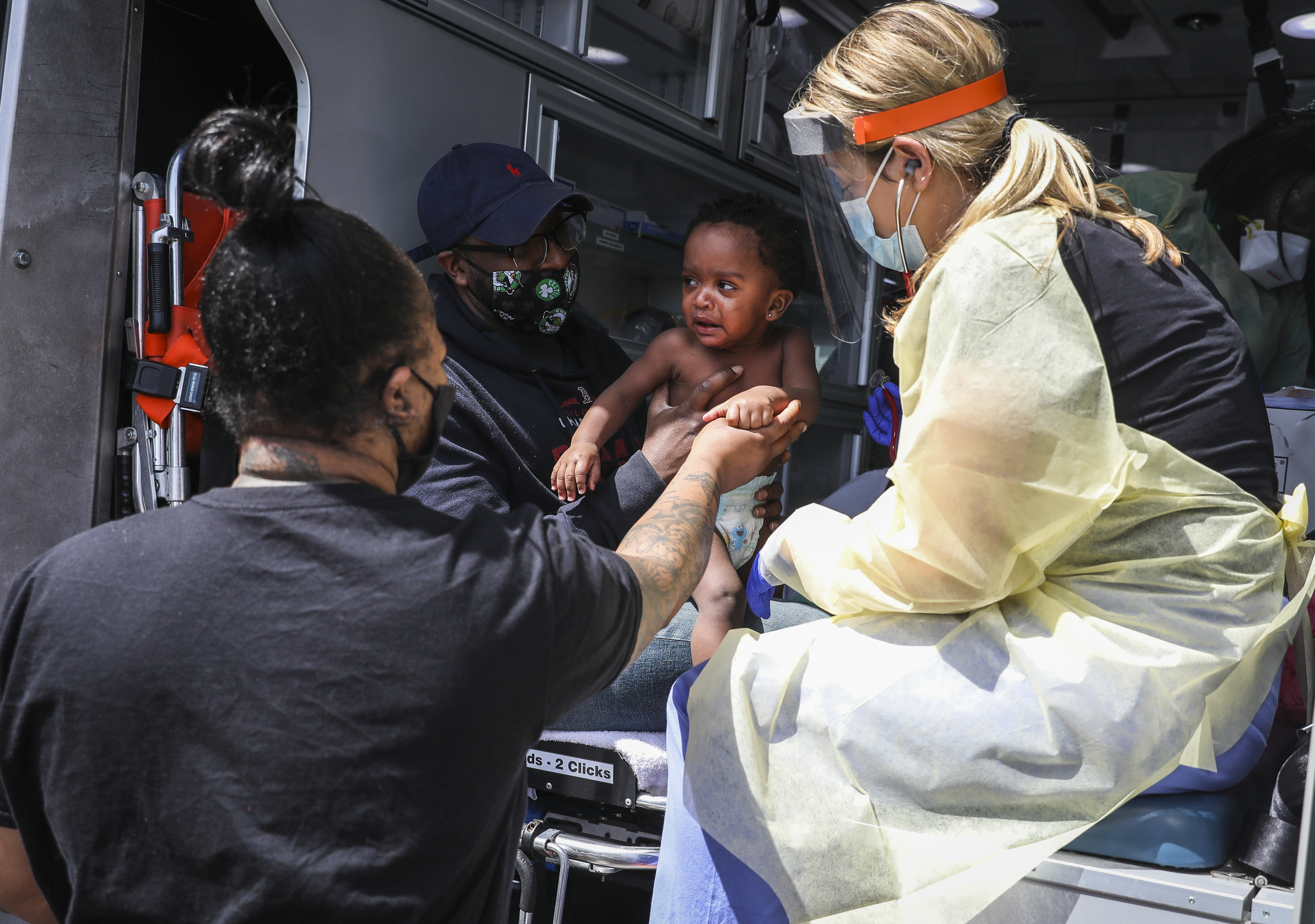 Chaude Johnson (left) and her husband Khalid held onto the hand of their daughter, 1-year-old Kyle Johnson, after Dr. Rachel Sagor performed a routine health checkup in the back of an ambulance.