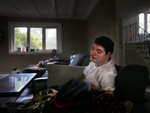 Dino Coppola in the living room of his family’s home, the windows of which face the Lasell College athletic field.