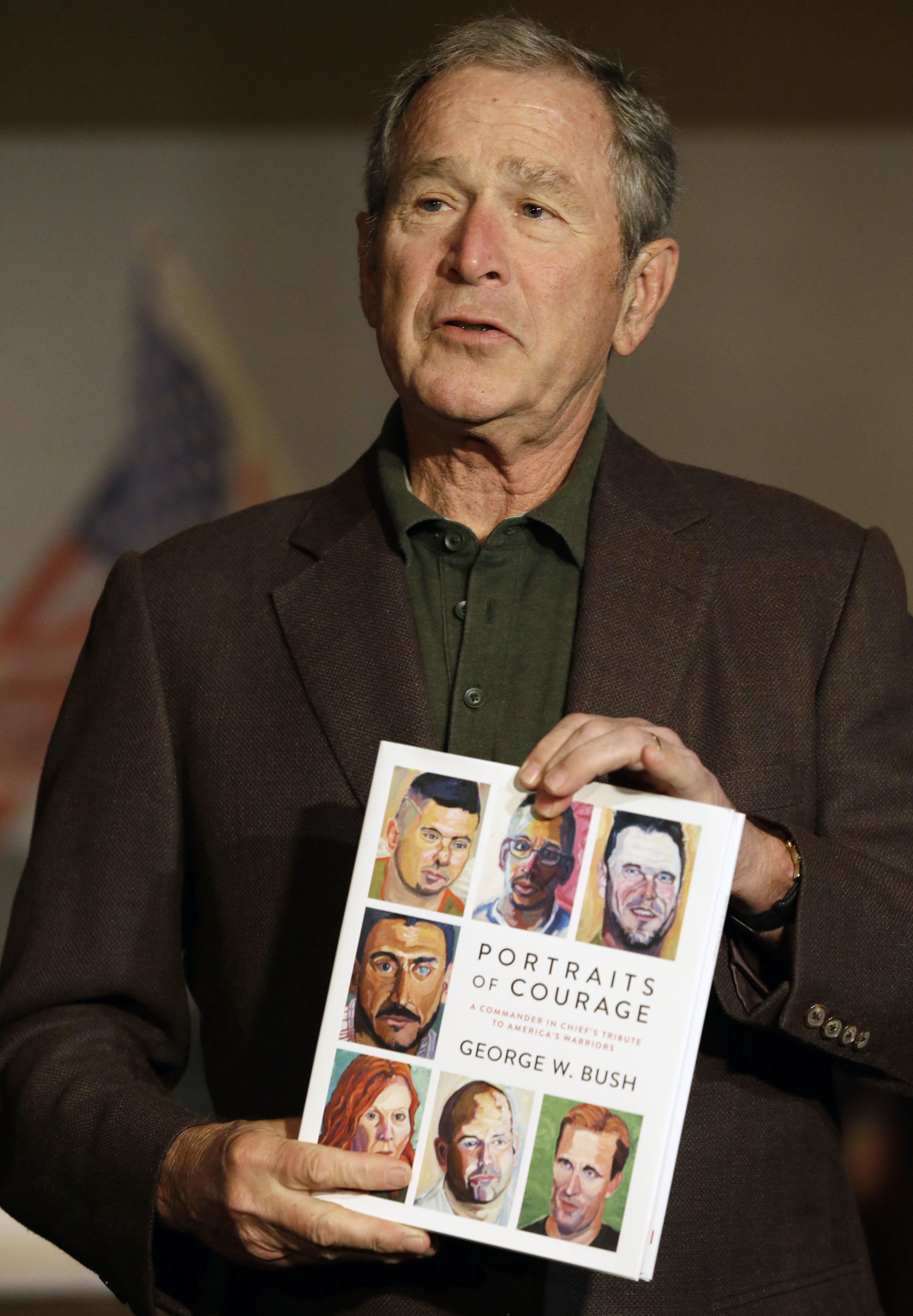 Former president George W. Bush held a copy of his new book during a press preview of an exhibition of his paintings of military veterans in Dallas on Tuesday.