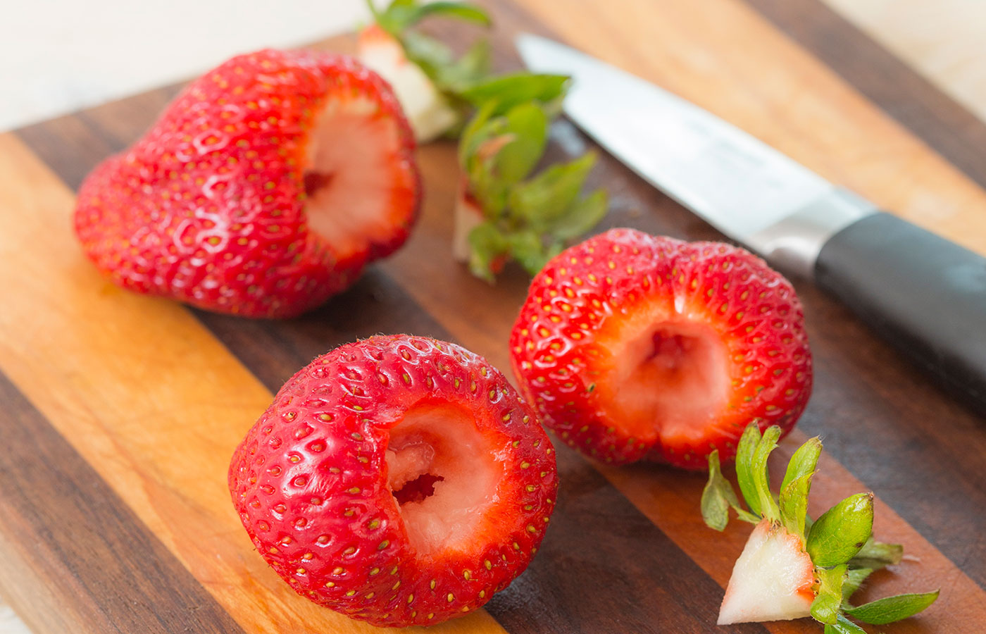 When hulling strawberries, lots of people just lop off the whole top of the berry, which wastes a lot of fruit. For less waste, use the point of a paring knife to cut down around the leaves in a tight V.