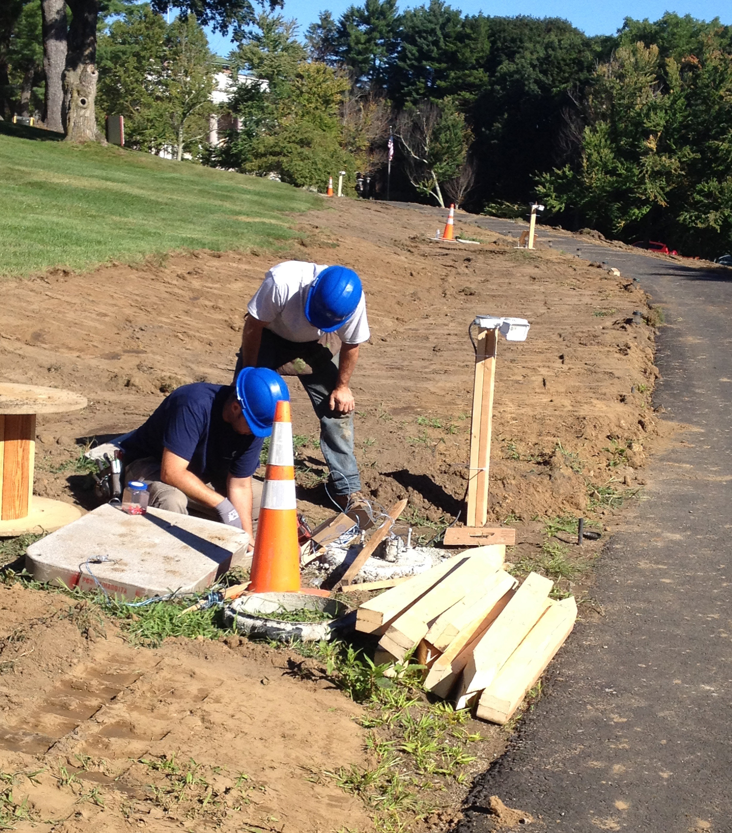 Workers prepared the “Great Walk,” curving along the Great Lawn that fronts the Regis campus, for the installation of lights that are part of the Weston expansion.
