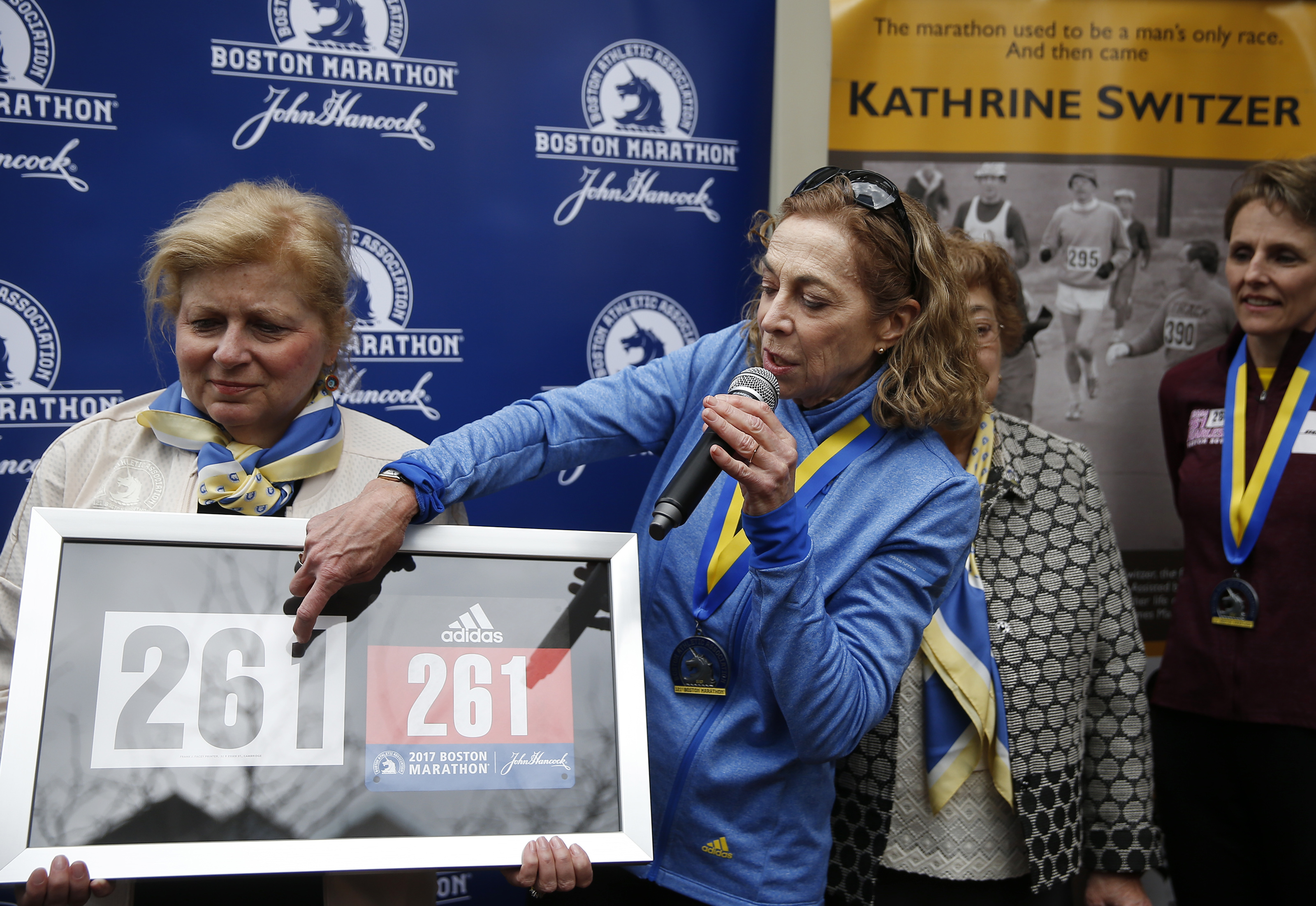Kathrine Switzer, right, points to her bib number being held by BAA President Joann Flaminio as she thanks the crowd during a ceremony to have her bib number, 261, retired.