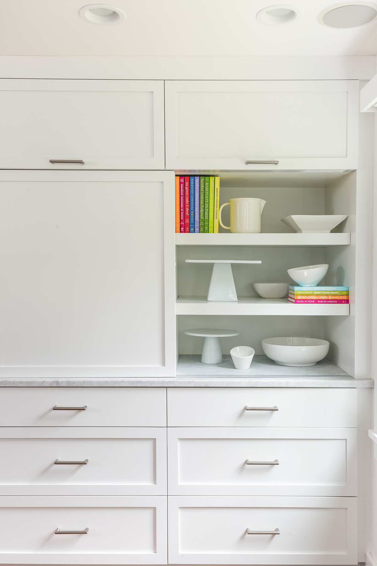 Panels slide along grooves cut into the marble countertop, hiding small appliances. “They wanted to cut clutter,” says architect Alissa Hike Harris. “Things are still accessible but out of sight.”