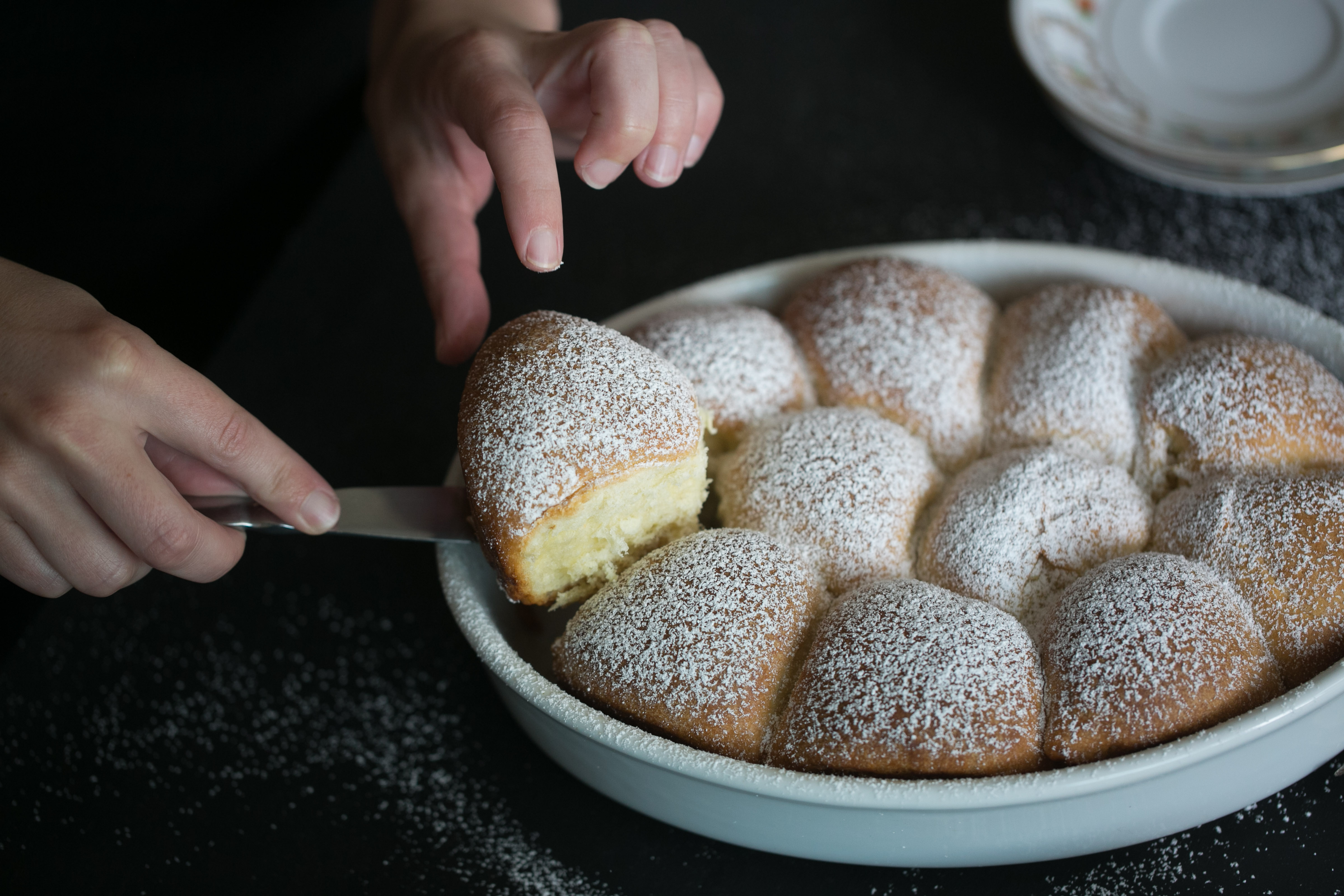 The buns are placed in a dish and baked. After they cool, they are dusted with confectioners’ sugar and served.
