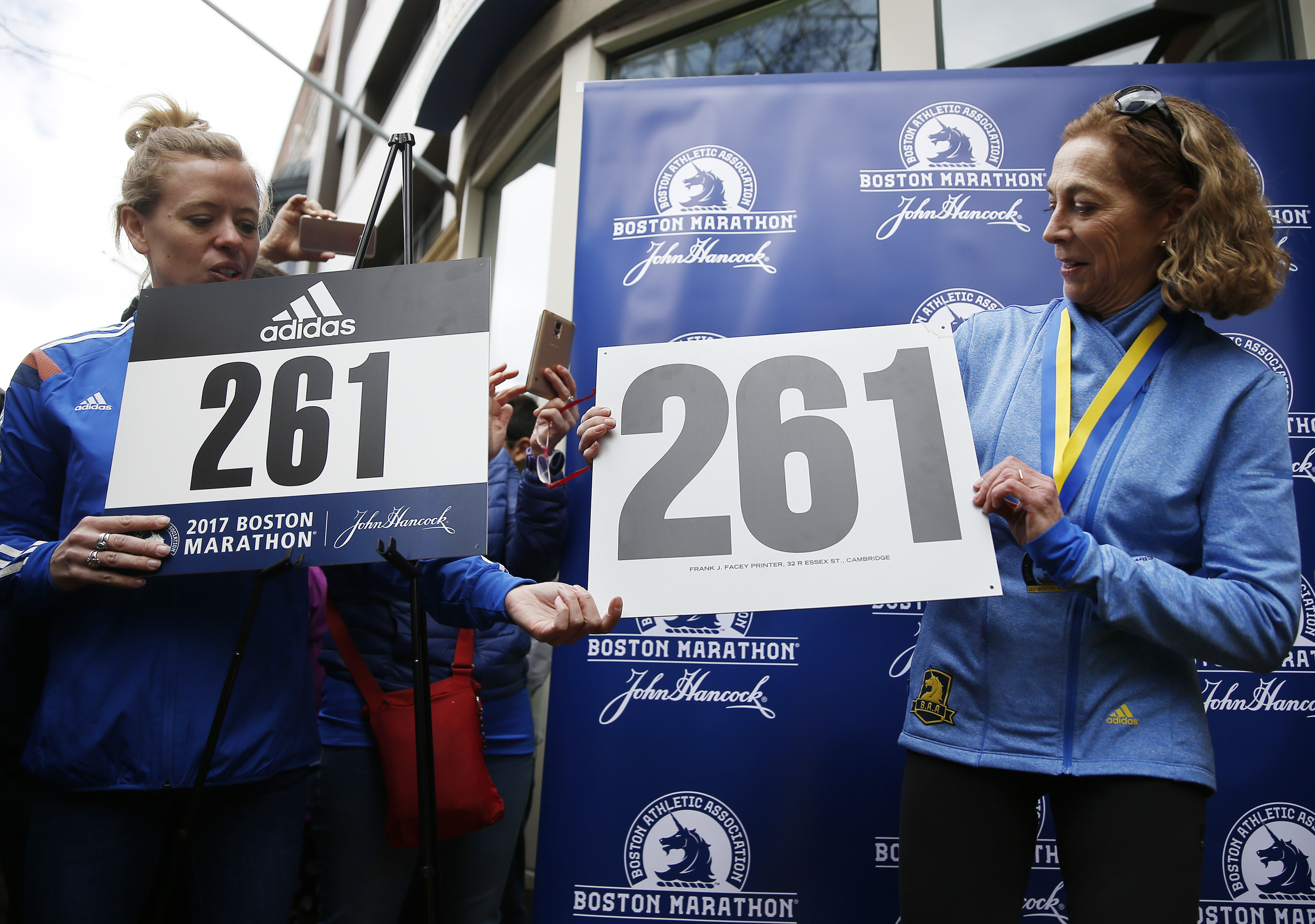 Kathrine Switzer, right, holds a reproduction of her original bib number, 261, during a ceremony to have her bib number retired.