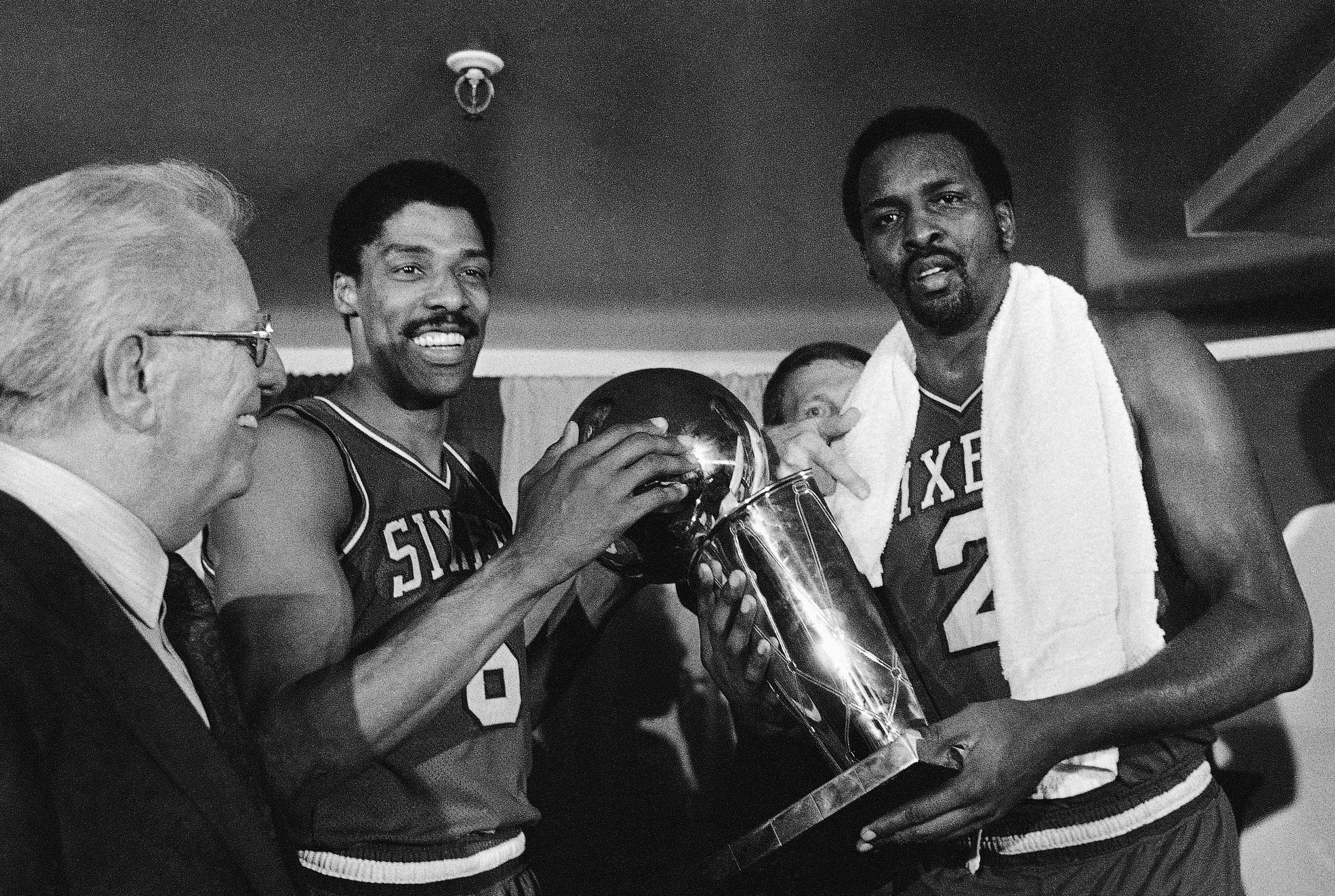 Julius Erving (left) and Moses Malone held the NBA Championship trophy after defeating the Lakers in 1983.