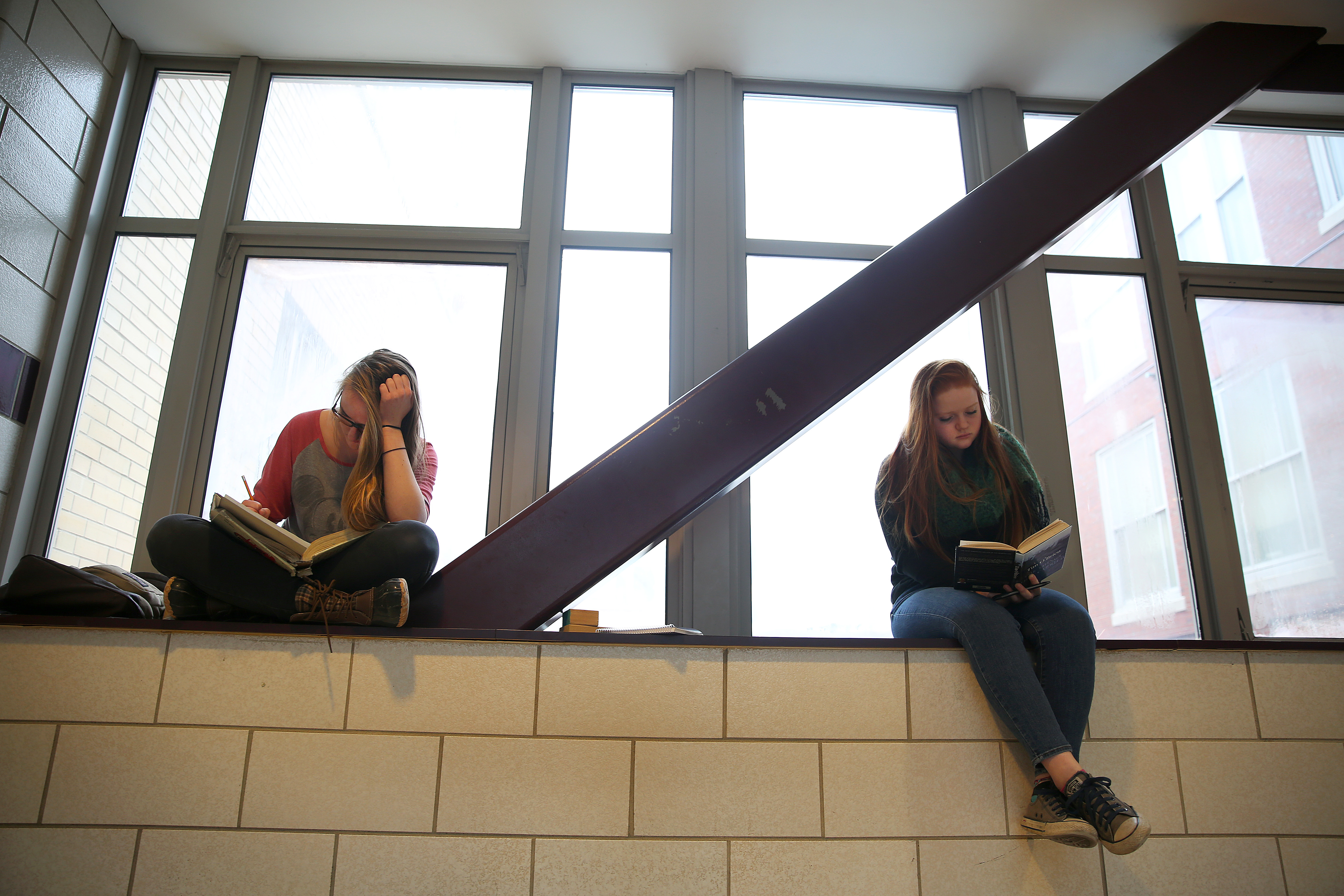 Molly O’Halloran (left) did geometry homework and Nora Davis read a book for English. Students speak often about the school’s pressure-cooker academic environment.