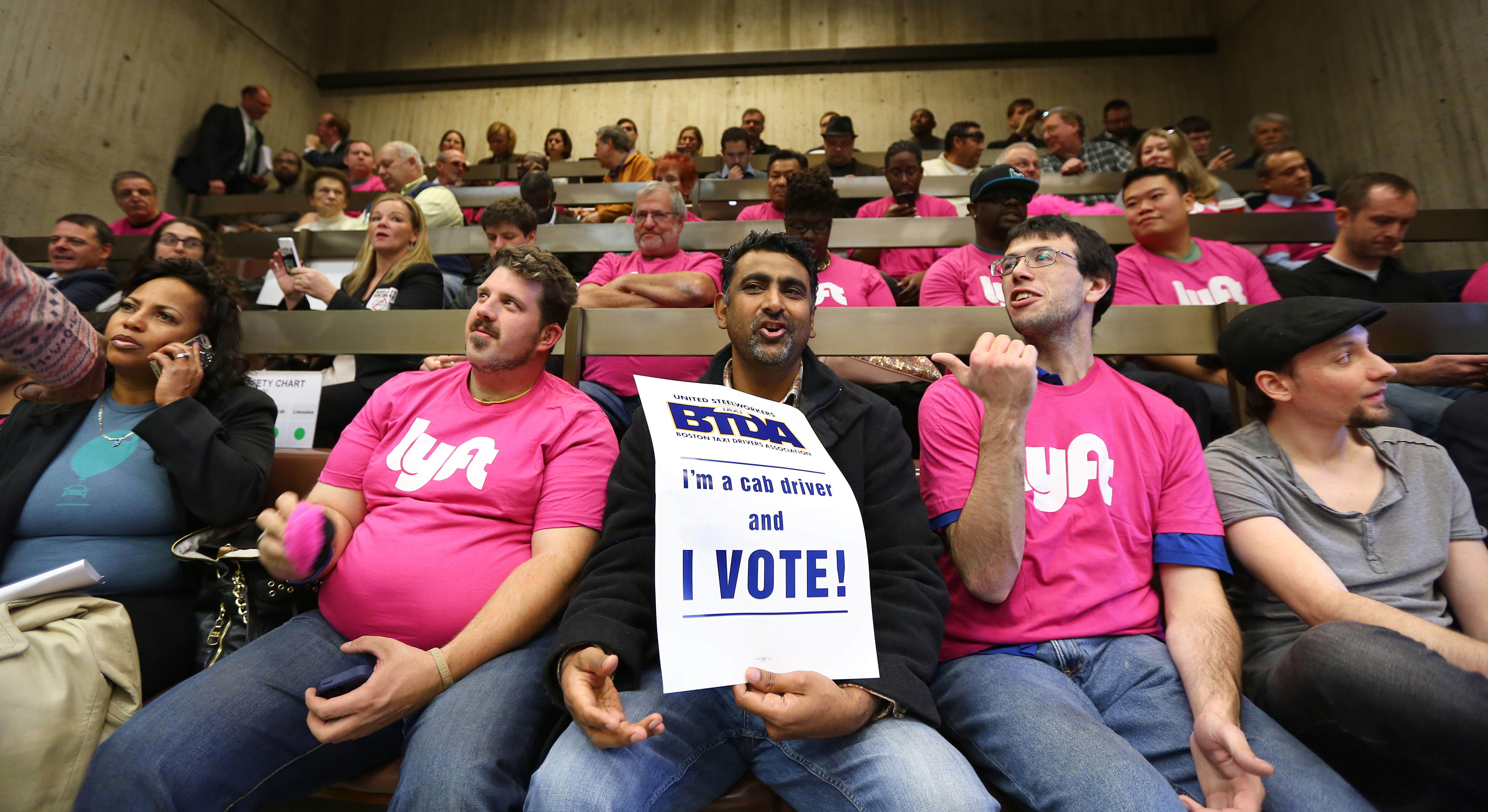 Boston cab driver Parmjit Singh sat among his Lyft and Uber competitors Monday. Cab drivers want ride-sharing drivers to be subject to the same consumer and worker protection rules.