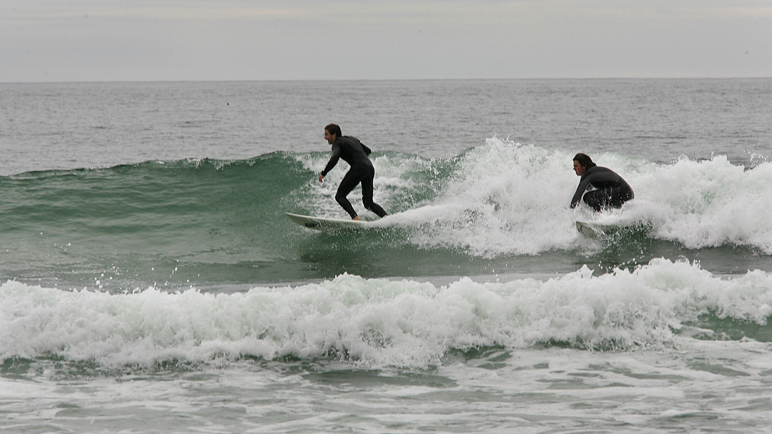 At Scarborough Beach State Park, surfers work the waves on a gray day.