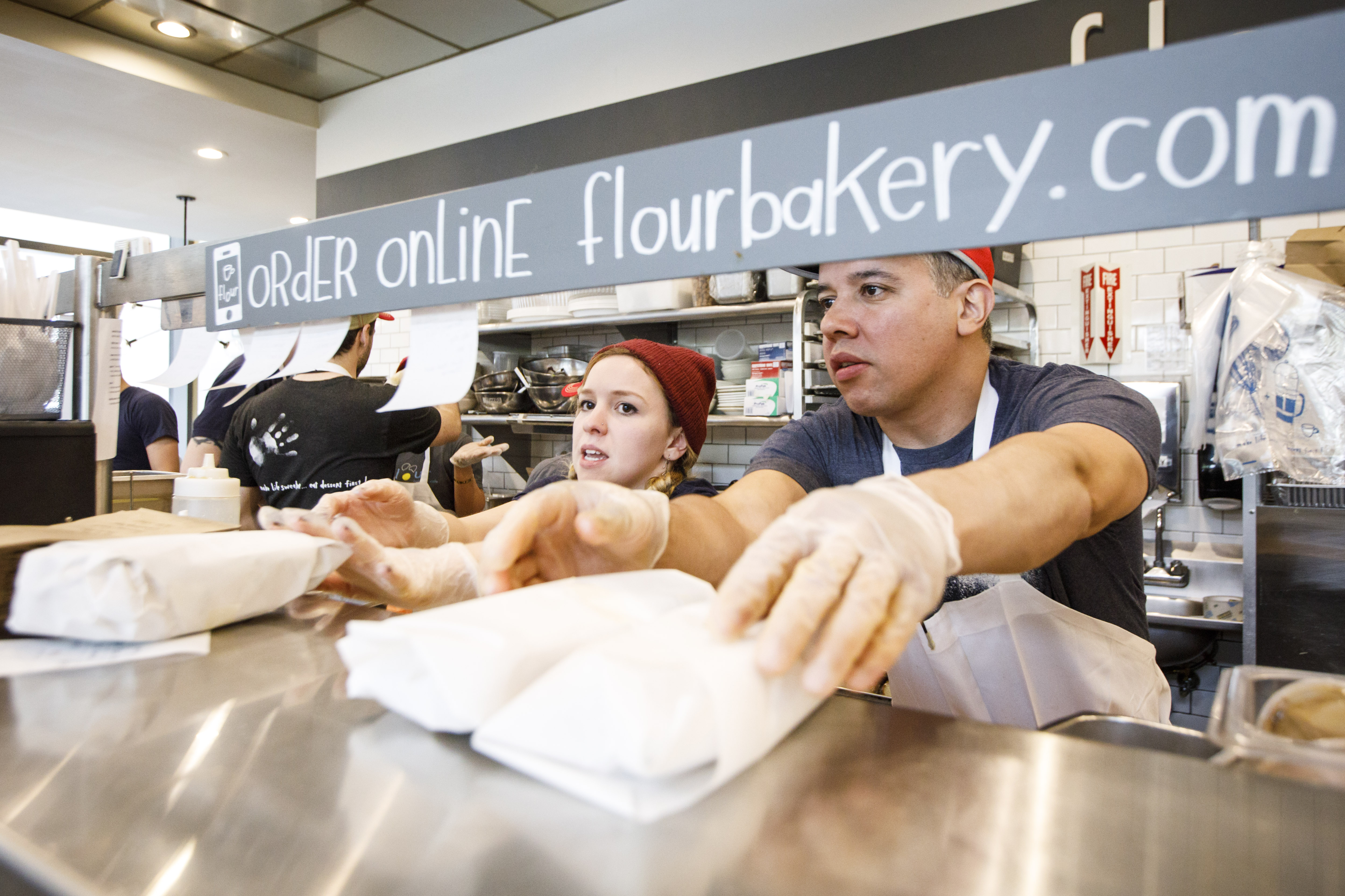 Kitchen staffers delivered food orders to the counter at Flour Bakery in Boston, an establishment that takes online orders as well as in-person ones.
