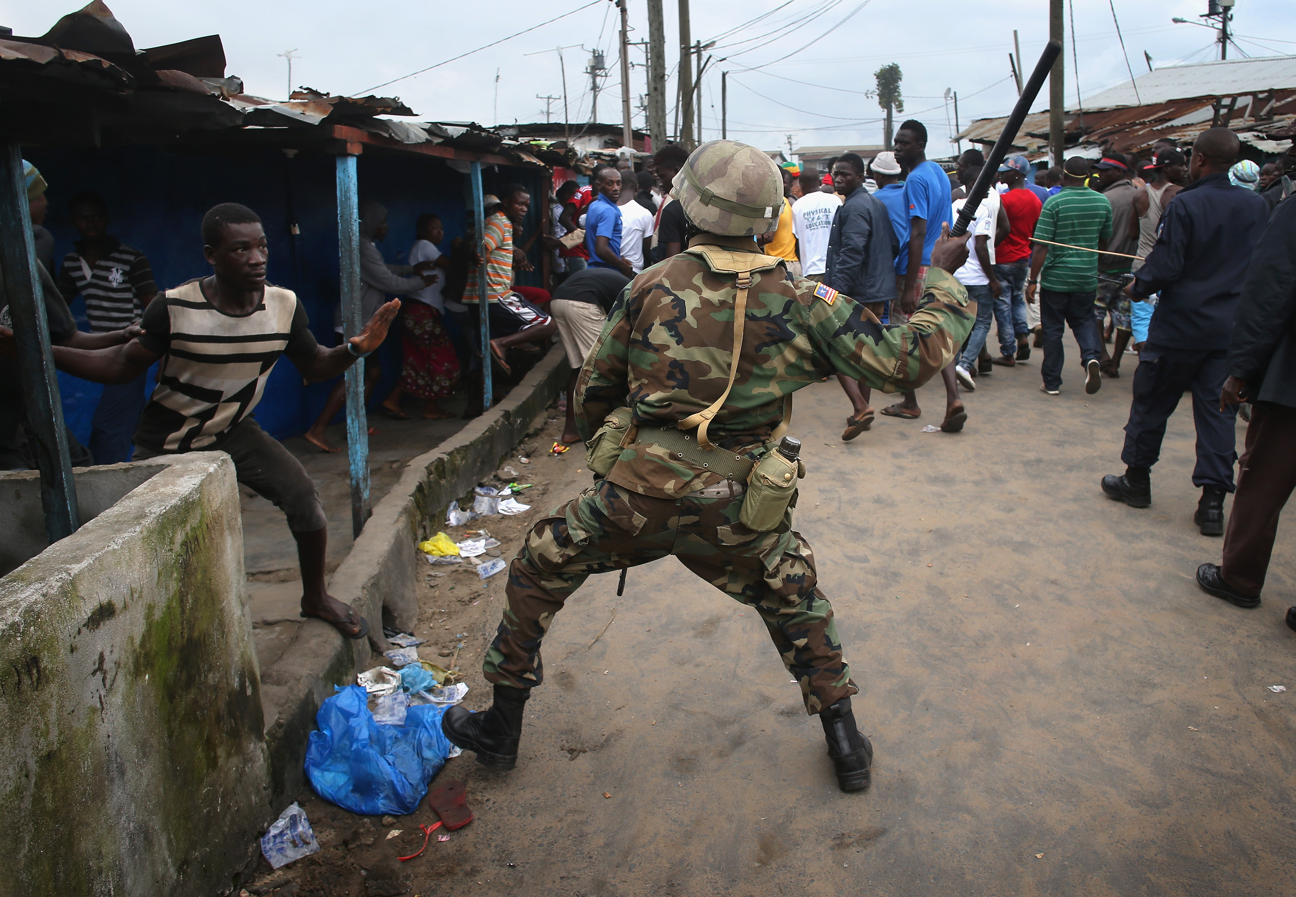 A Liberian Army soldier, part of the Ebola Task Force, beat a local resident while enforcing the quarantine.