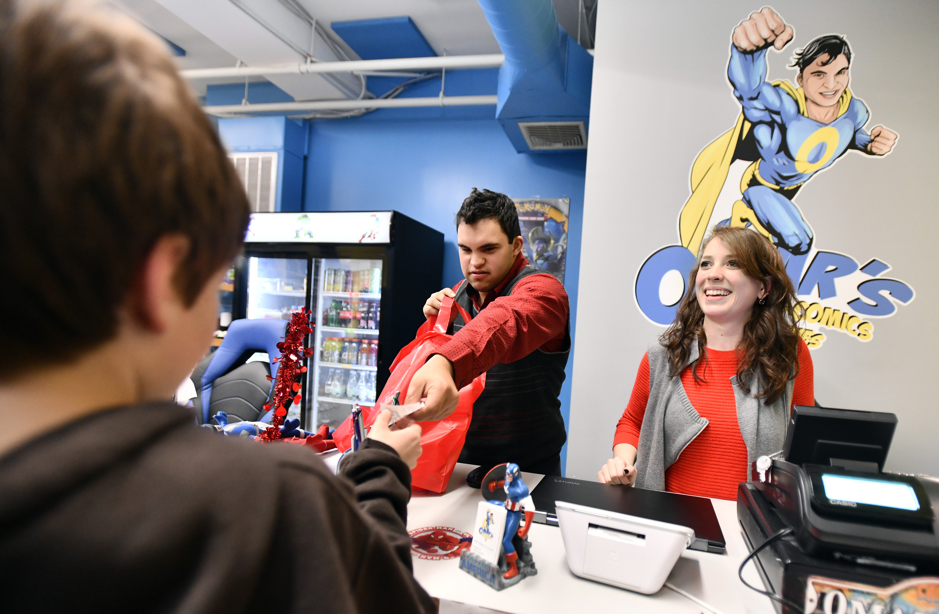 Store owner Omar Masood and manager Sally Hoops wait on a customer at Omar’s World of Comics & Hobbies.