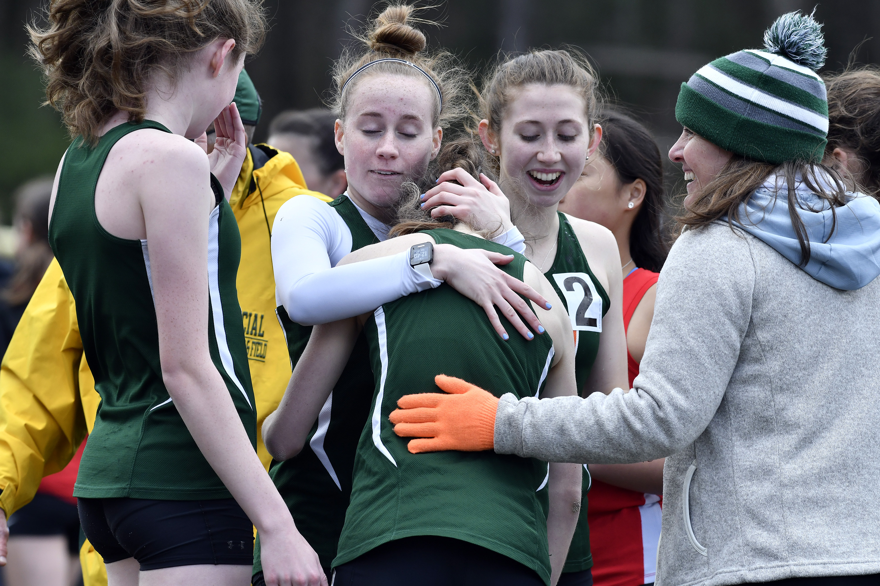 Hopkinton's Caroline Estella (left) and coach Jean Cahn congratulate Schuyler Gooley (center) who ran the last leg of the distance medley at the MSTCA Division 2 relays.