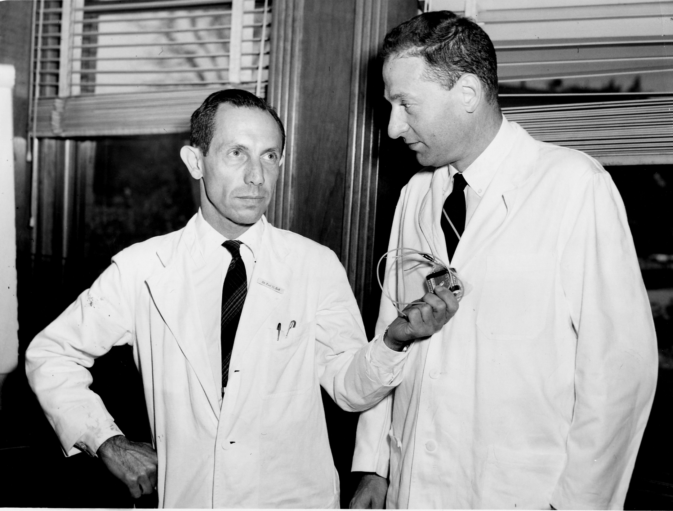 Dr. Paul Zoll (at left) holds an electrical apparatus successfully used in heart patients.
