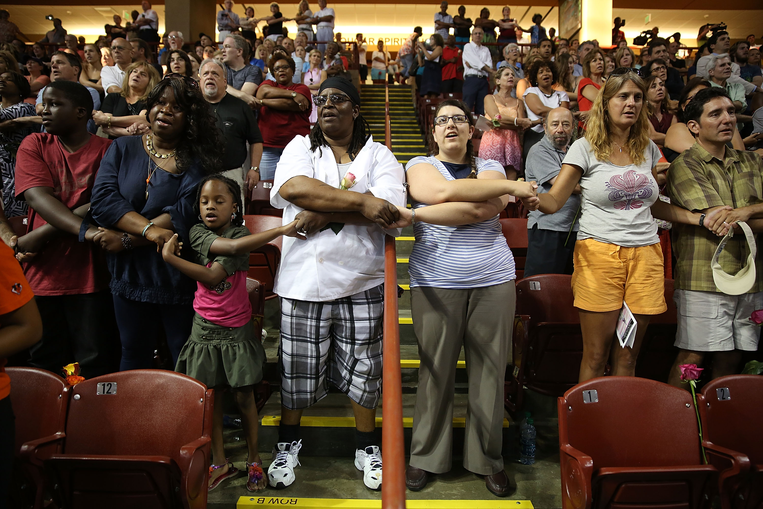 People join hands during a prayer vigil at the TD Arena Friday in Charleston.