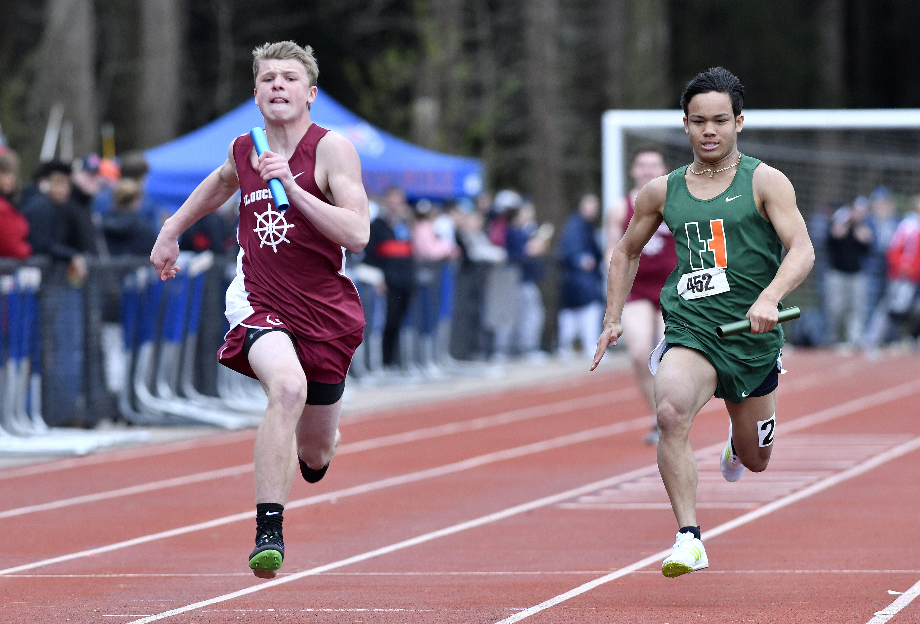 Luke Smith of Gloucester (left) and Sebastian Losada of Hopkinton place finish first and second for their teams in their heat of the 100 at the MSTCA Division 2 relays at Walpole High.