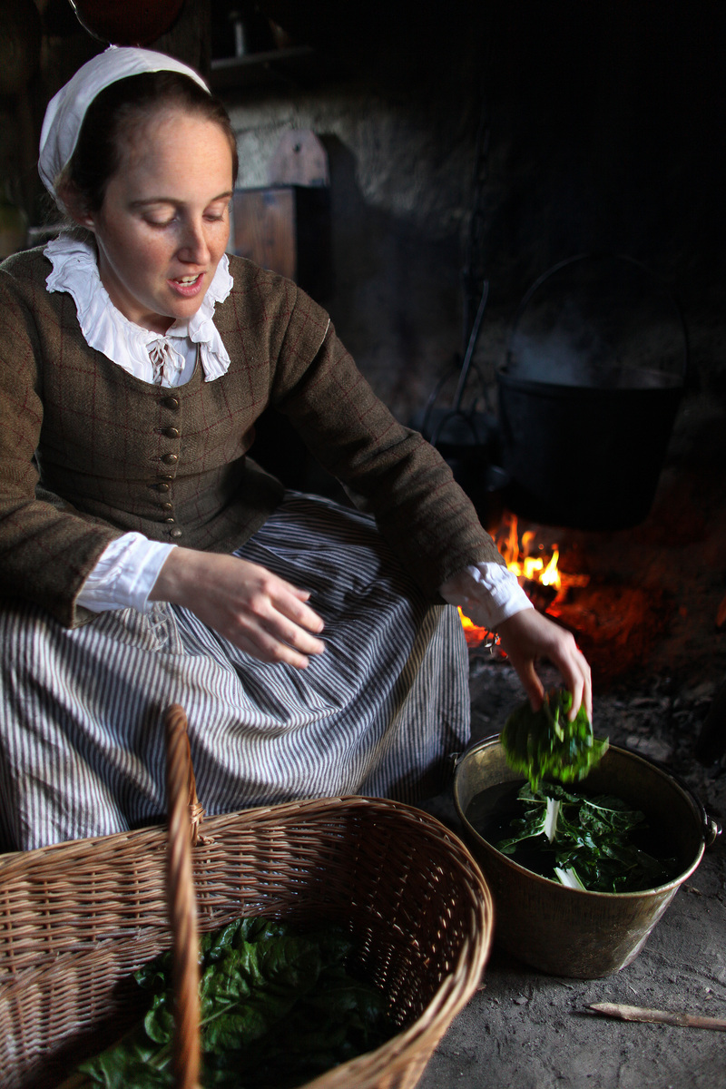 A Plimoth Plantation actor, as Mary Winslow, cooks a meal.