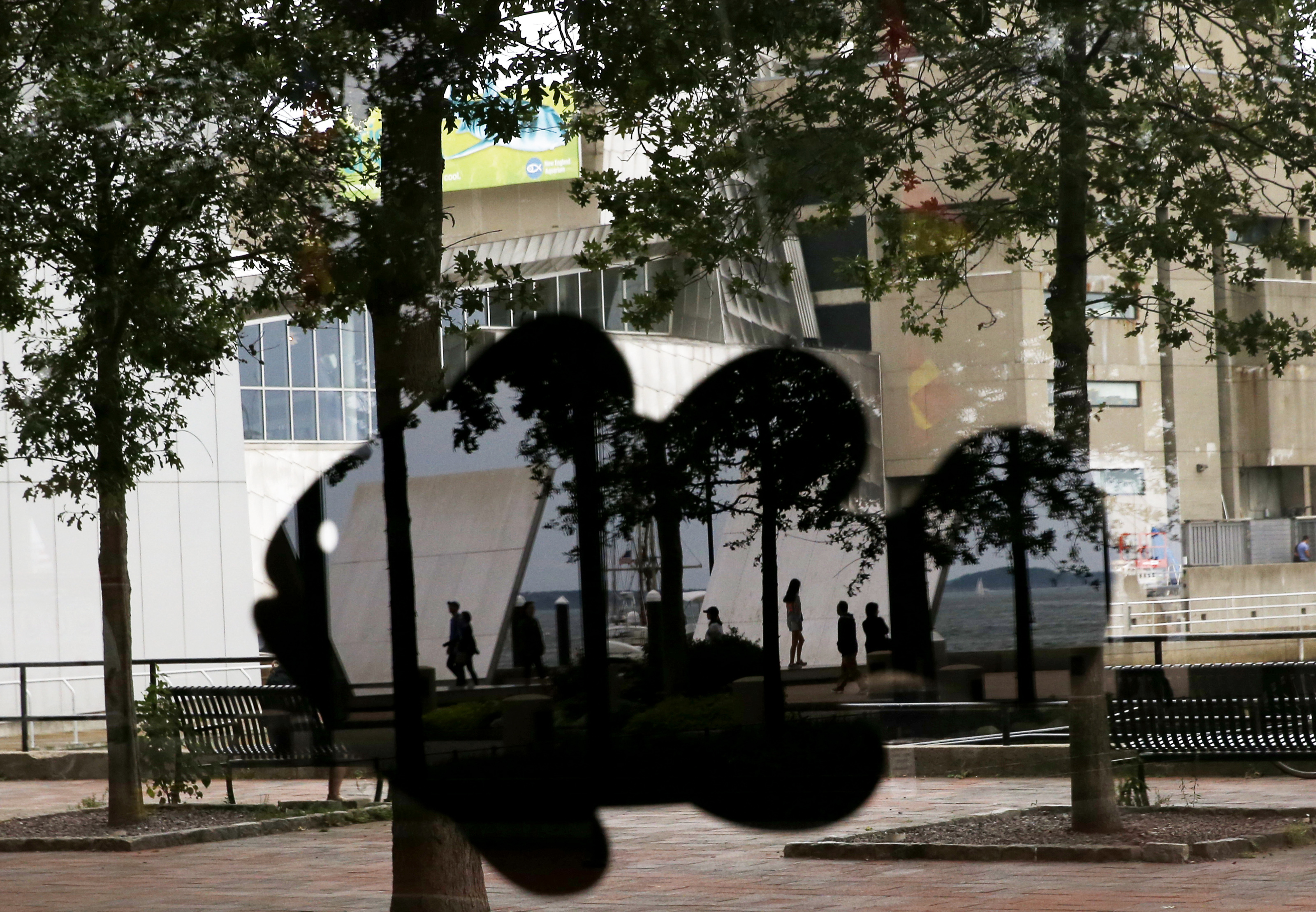People are reflected in a cutout of a fish stuck to one of the windows inside the Boston Harbor Garage.