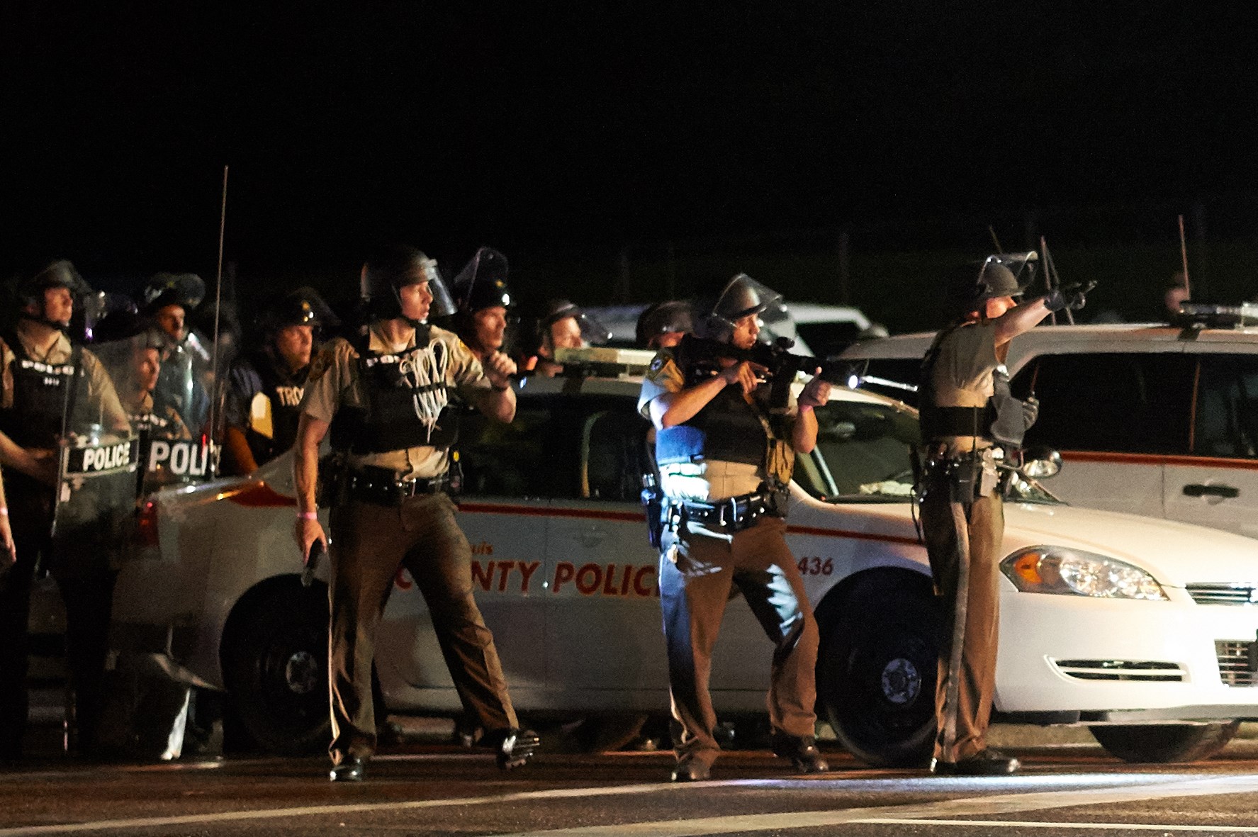 A St. Louis County police officer directed an oncoming car looking to evacuate the area after a police-involved shooting during a protest on West Florissant Avenue in Ferguson, Missouri.