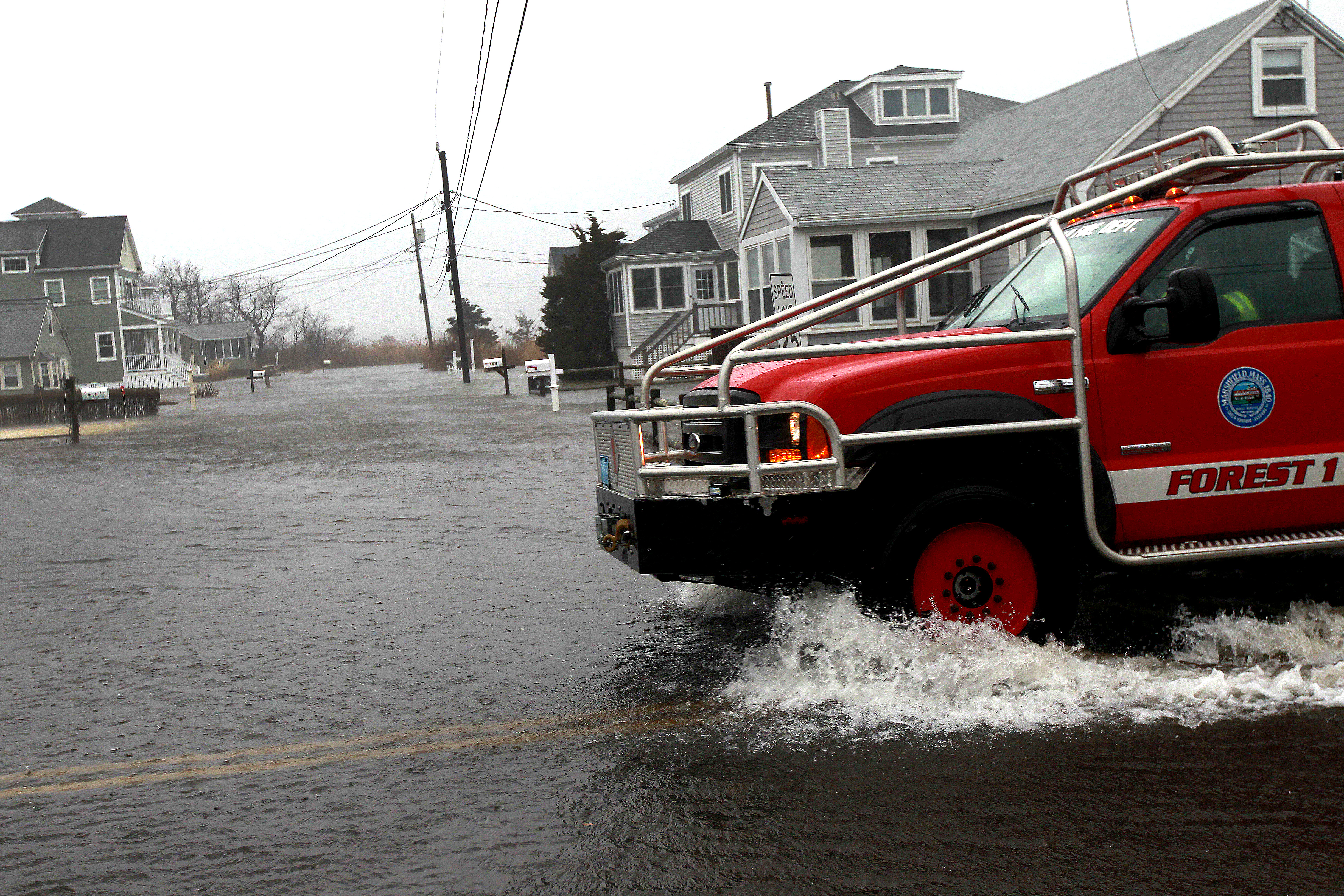 A Marshfield Fire Department vehicle patrolled a flooded neighborhood near Rexhamme Beach on Friday,