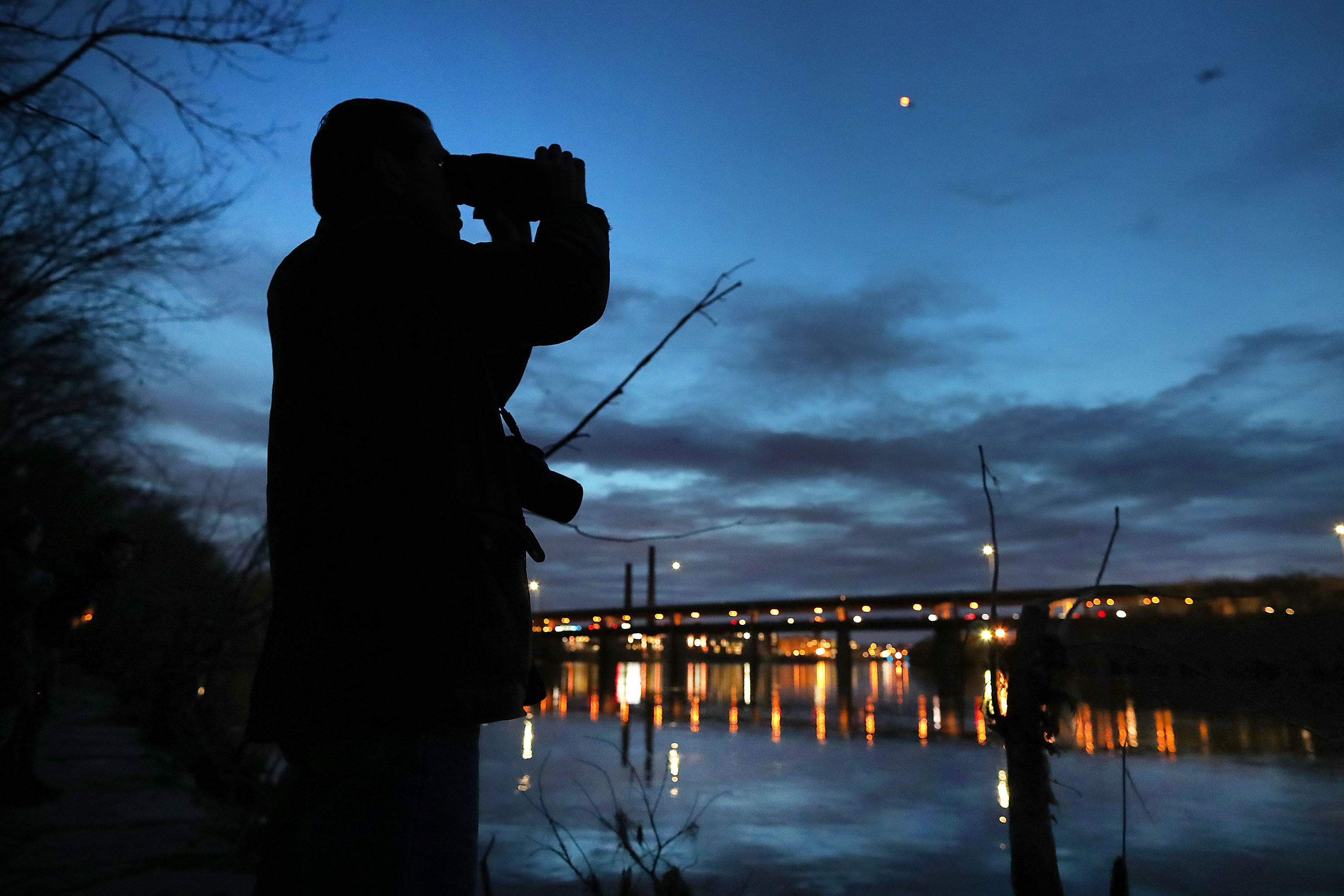 Craig Gibson used a night vision binoculars to check out the crows on the Lawrence side of the river.