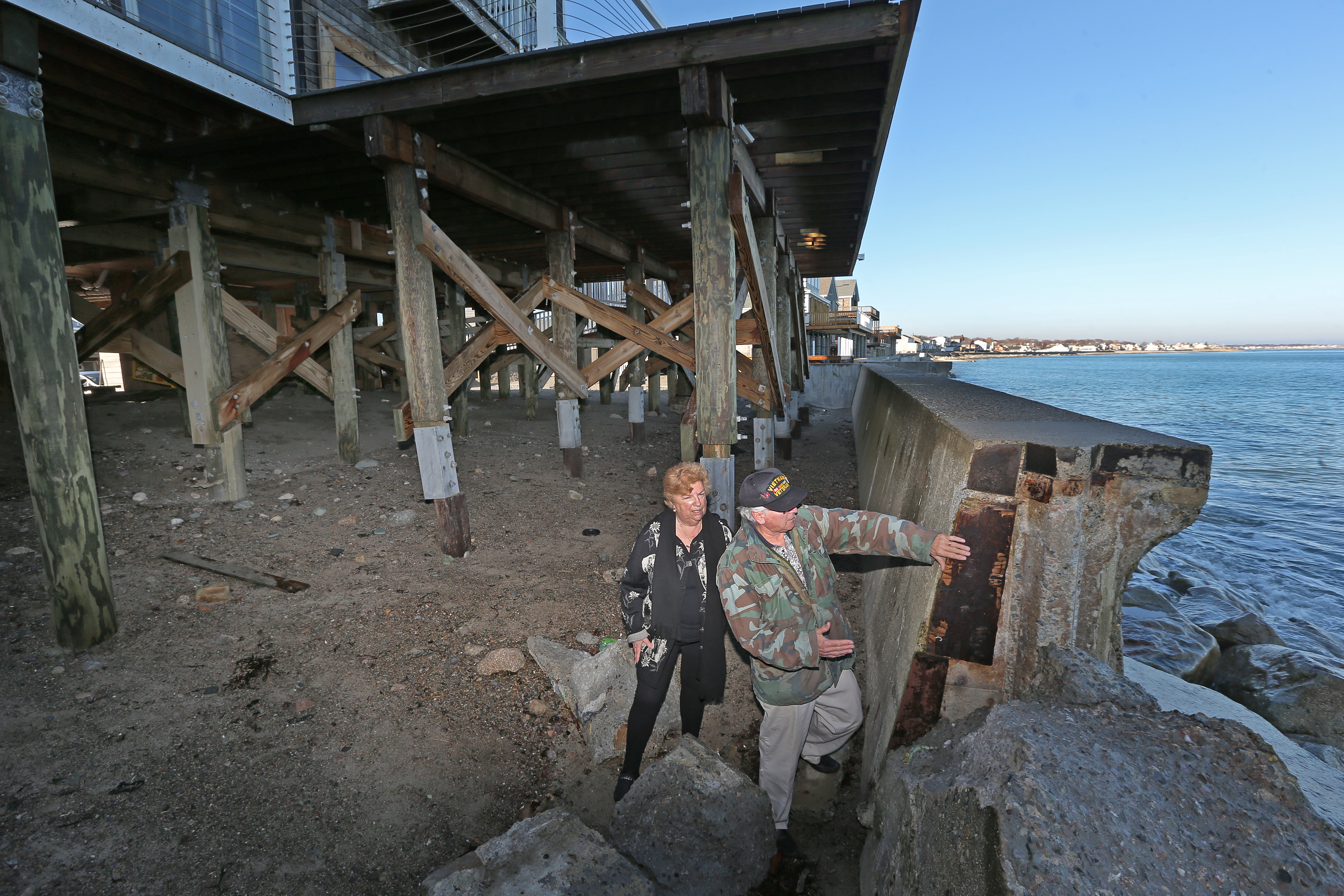 Doris Crary, a Scituate homeowner, looked at a sea wall that collapsed in a recent storm with her husband, Dennis Badore. Four out of six properties she owns were hit last year with $600 to $900 increases in annual insurance premiums.
