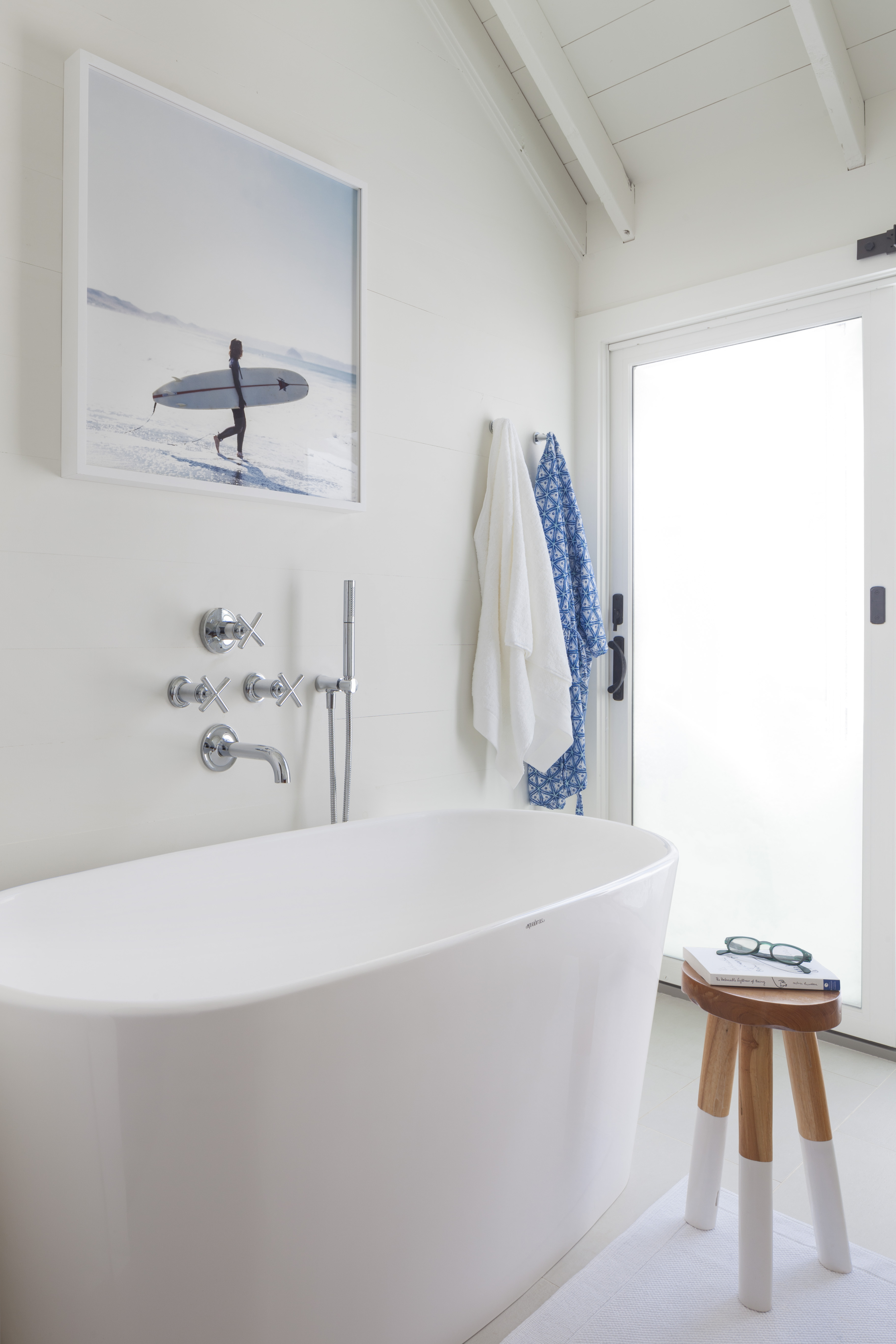 In the master bath, a photo by Anthony-Masterson hangs above Kohler Purist fixtures, wall-mounted to save space. The dip-dyed reclaimed teak stool is from Serena & Lily.