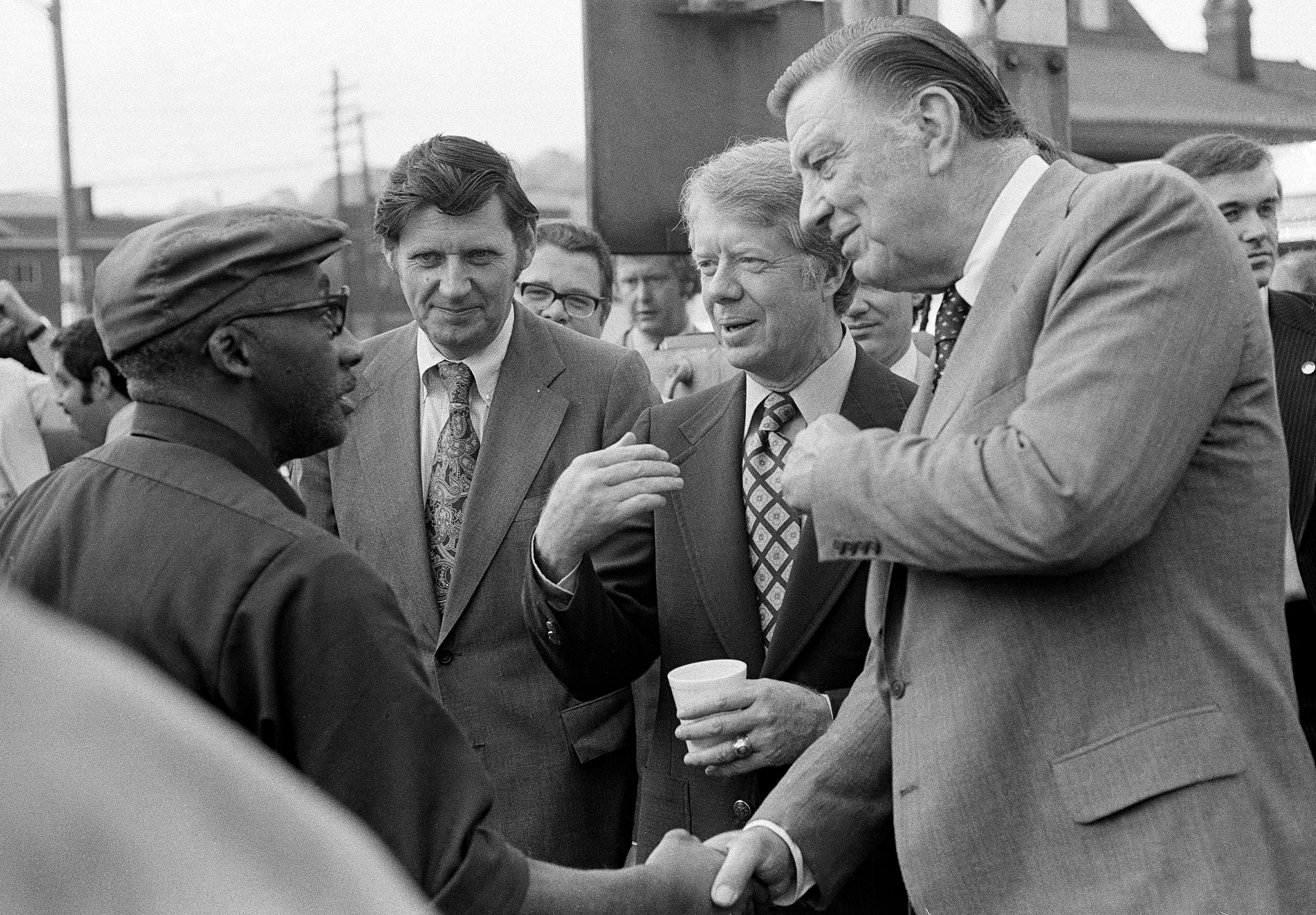 Jimmy Carter (center) held a cup of coffee and met workers during a shift change at a steel mill on April 21, 1976, in Pittsburgh, Pa.
