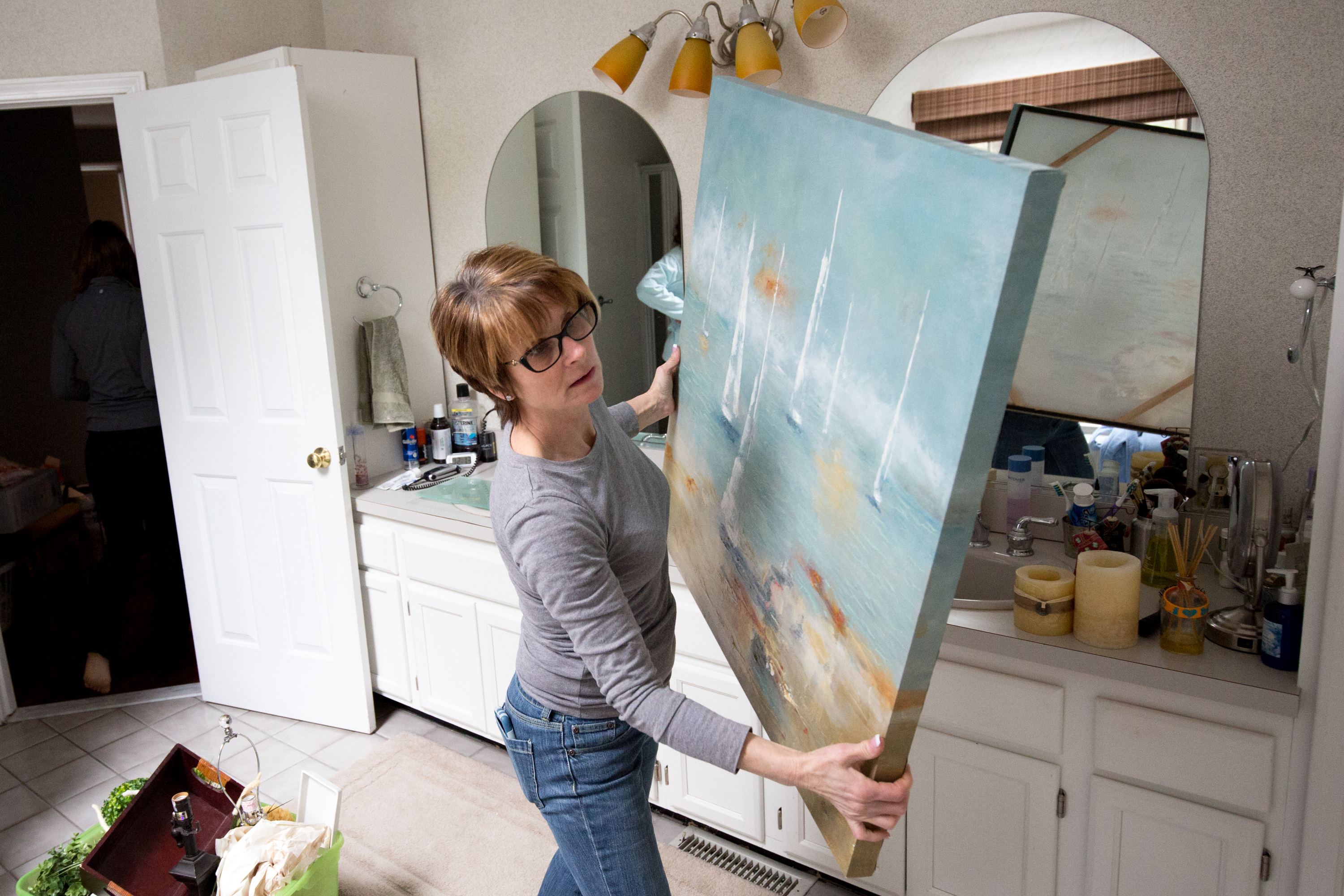 Jennifer Dabenigno moves a painting to a bathroom of a home in North Reading.